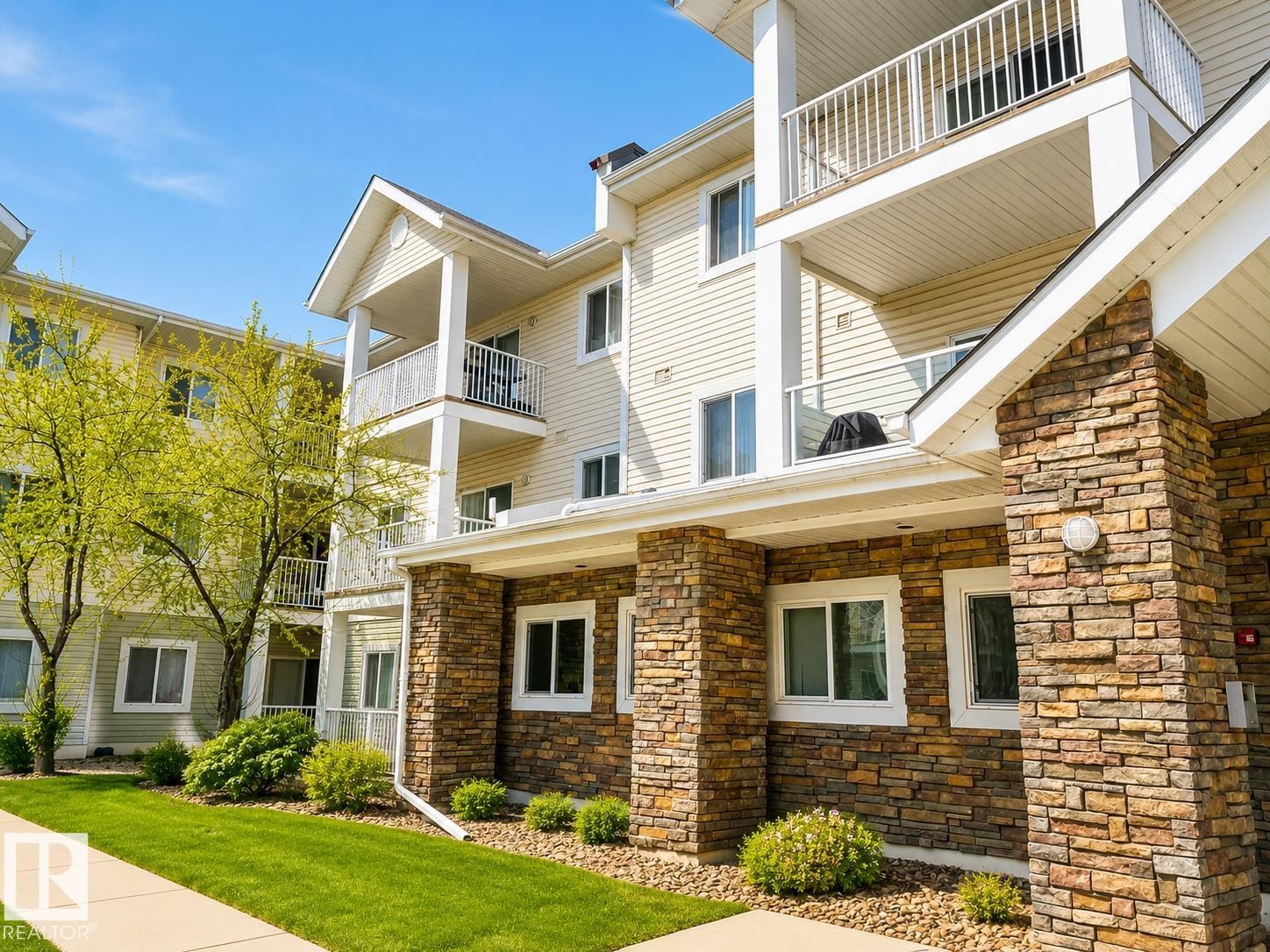 Multi-story building exterior featuring stone veneer columns and siding with multiple balconies - 336 9525 162 Avenue, Edmonton, AB - Outdoor With Balcony With Facade