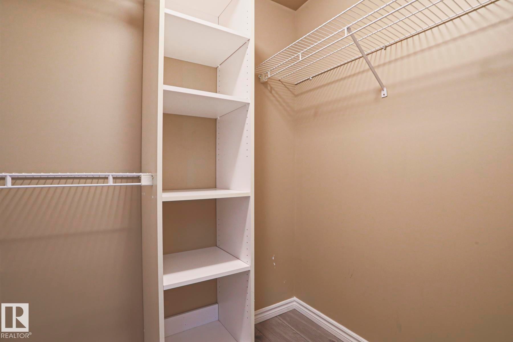 This closet features built-in white shelving units and hanging rods, providing ample storage - 201 10909 103 Avenue Nw, Edmonton, AB - Indoor With Storage
