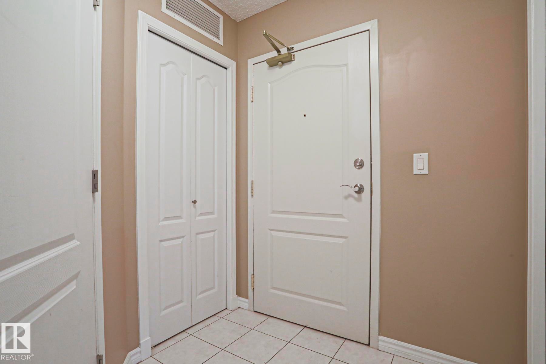 Entryway featuring a white door, a folding closet door, and tiled flooring - 201 10909 103 Avenue Nw, Edmonton, AB - Indoor Photo Showing Other Room