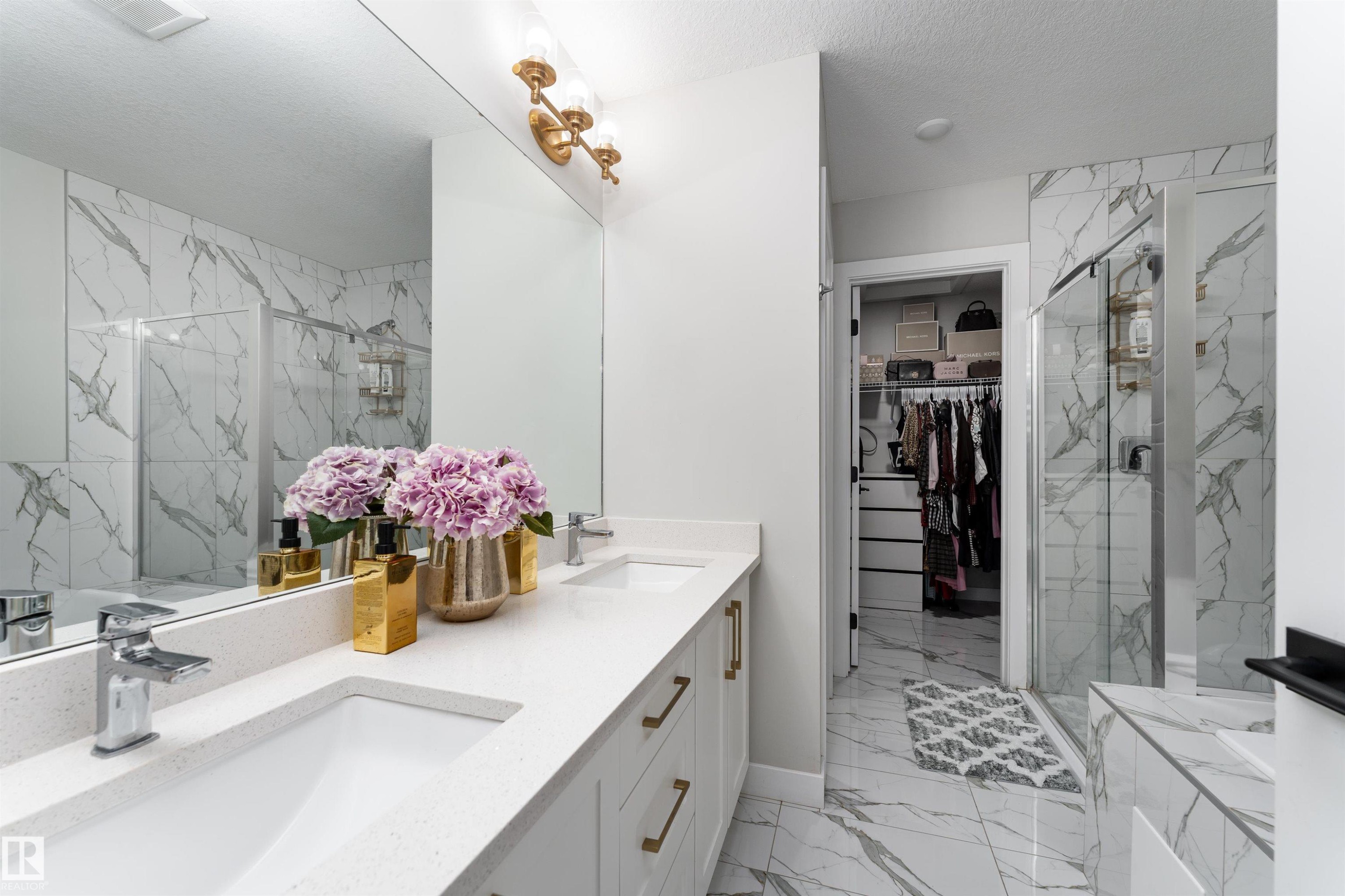 A bathroom featuring a dual vanity with white countertops, gold-toned hardware, and a large mirror - 993 Berg Pl, Leduc, AB - Indoor Photo Showing Bathroom