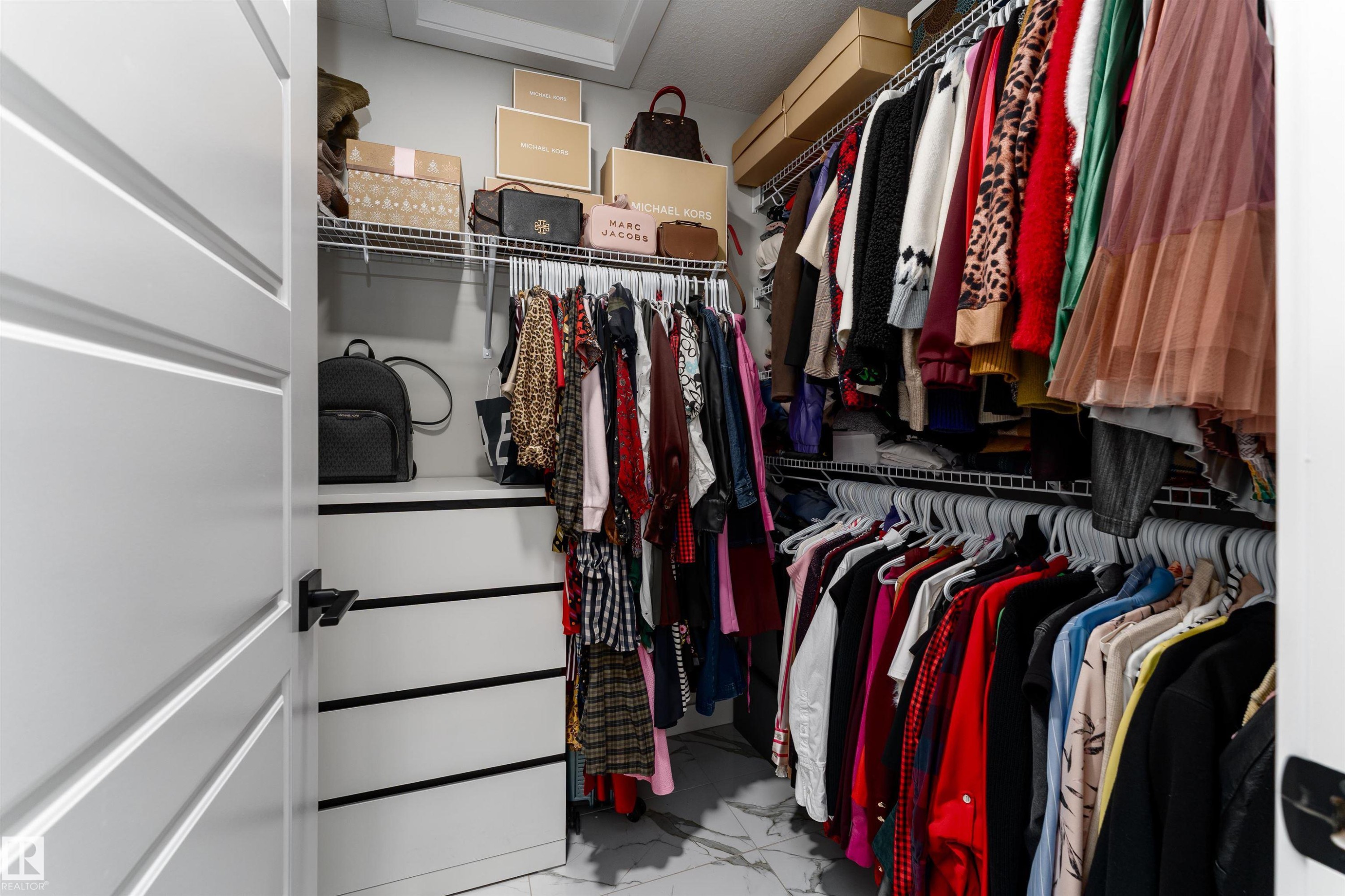 The property offers a walk-in closet with built-in shelving, wire racks for hanging items, and a white drawer unit - 993 Berg Pl, Leduc, AB - Indoor With Storage