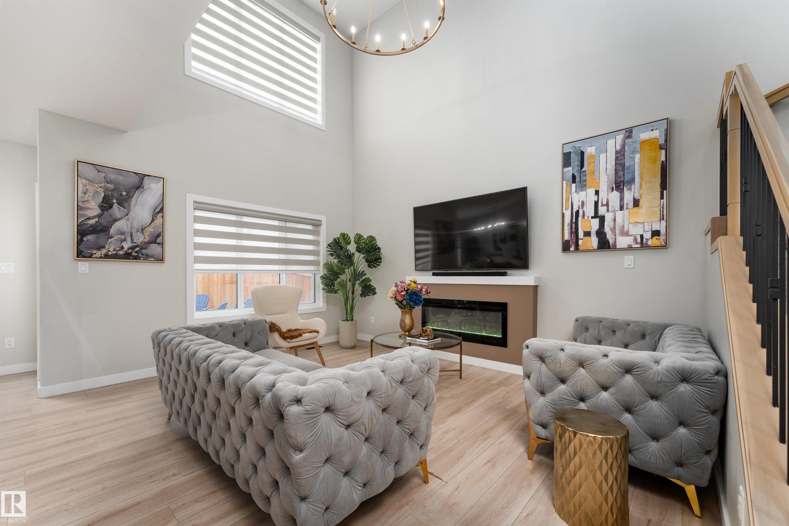 This living space features high ceilings, light wood-style flooring, and an electric fireplace - 993 Berg Pl, Leduc, AB - Indoor Photo Showing Other Room With Fireplace