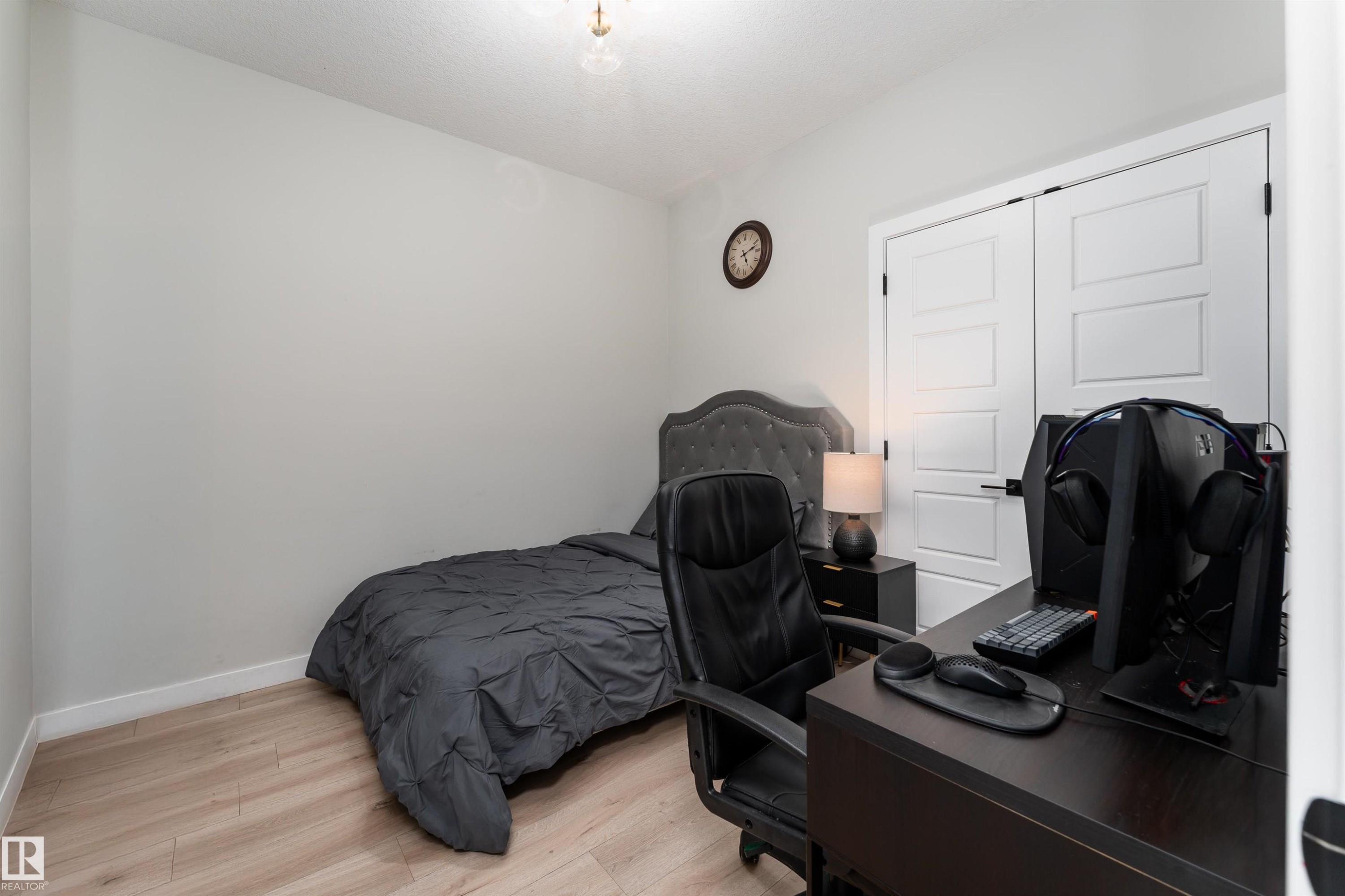 This room features light-colored walls, light wood-style flooring, and a ceiling light fixture - 993 Berg Pl, Leduc, AB - Indoor Photo Showing Bedroom
