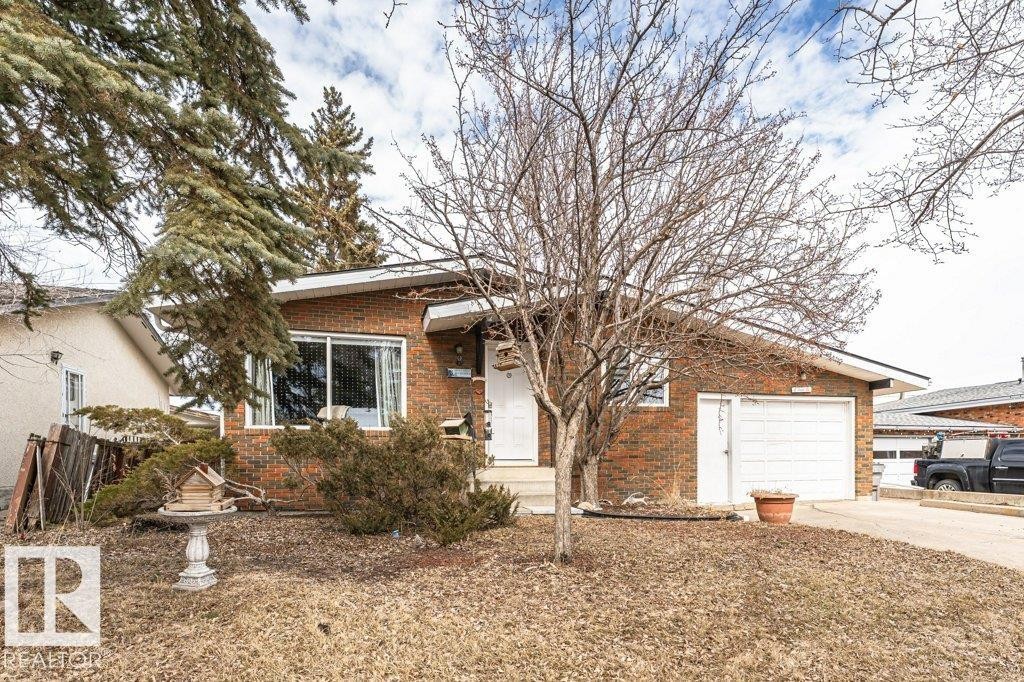 The property features a brick exterior, a driveway, and an attached garage with a white garage door - 8 Duke Drive, Lamont, AB - Outdoor