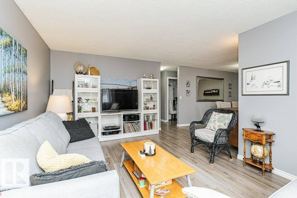 The living area features light-toned flooring, a light gray wall color, and a woven armchair with a light cushion - 8 Duke Drive, Lamont, AB - Indoor Photo Showing Living Room