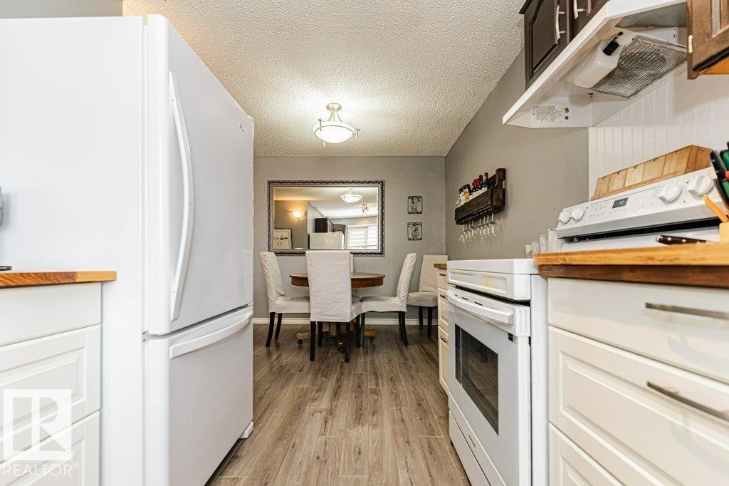 The kitchen features white cabinetry with wood countertops, a white refrigerator, and a white oven - 8 Duke Drive, Lamont, AB - Indoor Photo Showing Kitchen