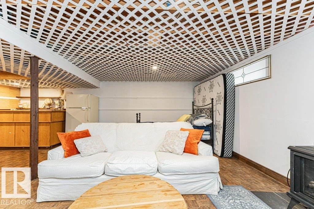 This versatile space features a white lattice ceiling, a wood plank style floor, and a window with decorative glass - 8 Duke Drive, Lamont, AB - Indoor Photo Showing Living Room