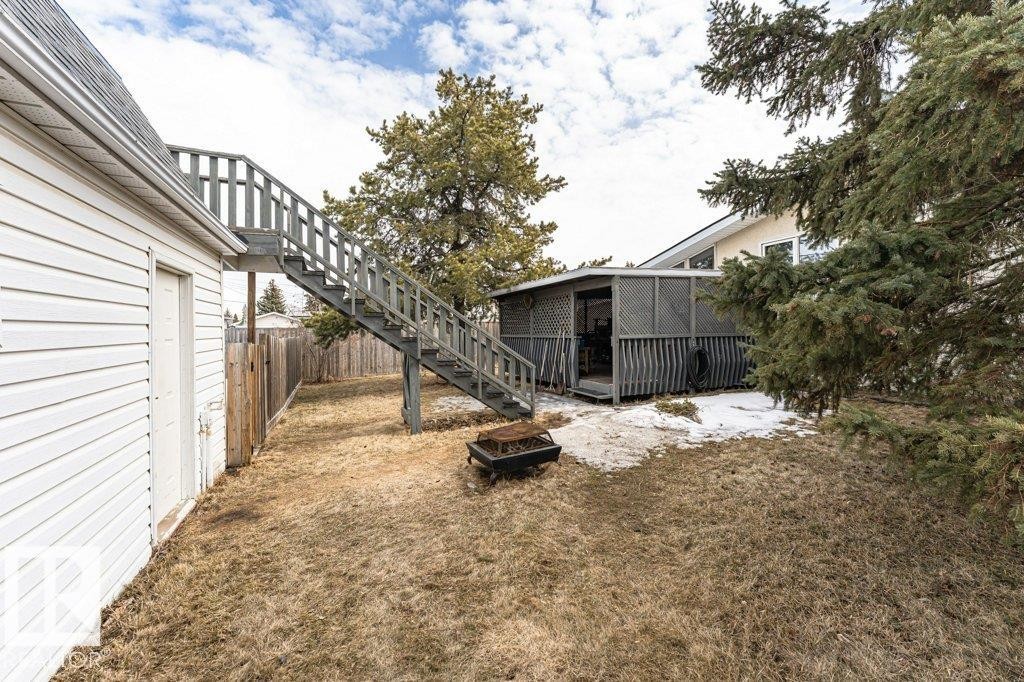 The property features a fenced yard, a detached outbuilding with a porch, and a staircase leading to an upper level - 8 Duke Drive, Lamont, AB - Outdoor