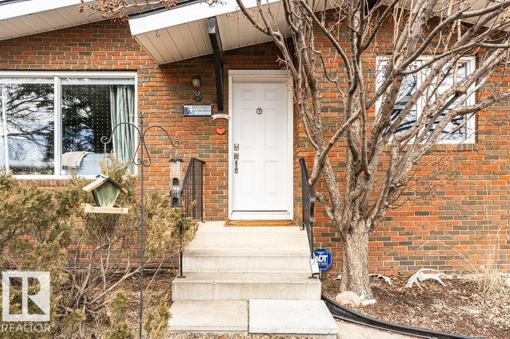 The property features a brick exterior with a white entry door and concrete steps - 8 Duke Drive, Lamont, AB - Outdoor