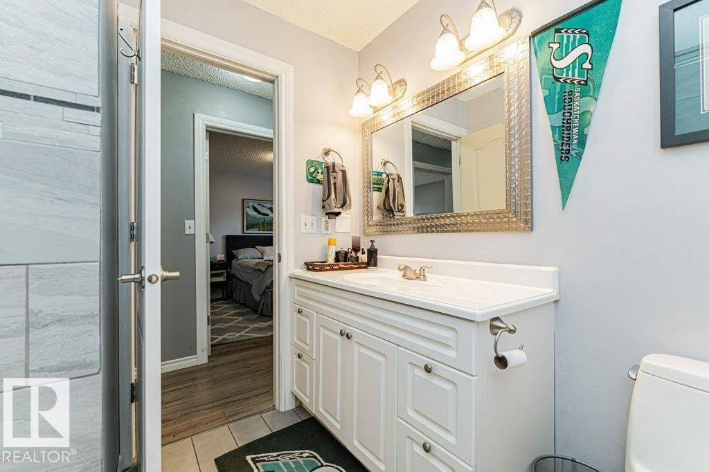 The bathroom features a white vanity with a white countertop and a framed mirror - 8 Duke Drive, Lamont, AB - Indoor Photo Showing Bathroom