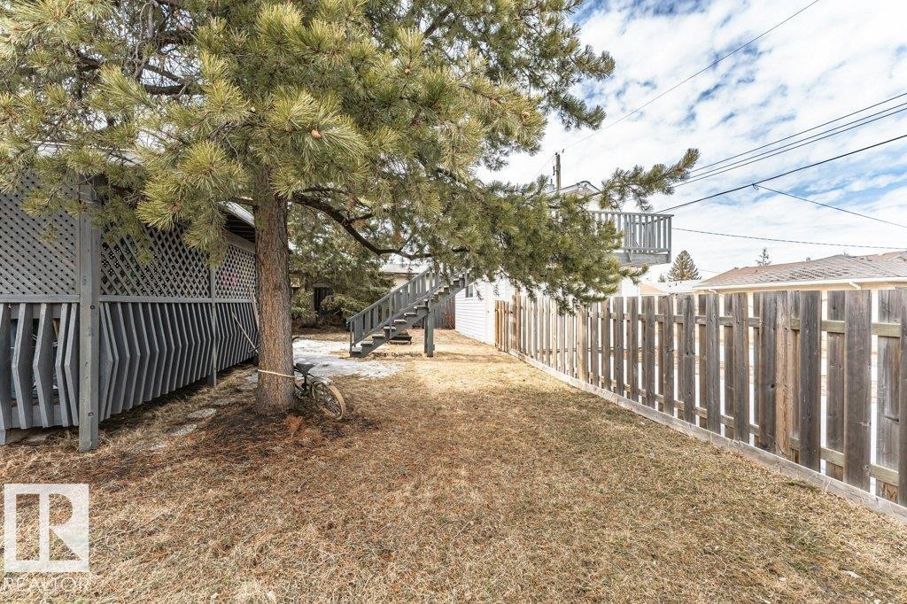 The property features a fenced yard, a mature tree, and outdoor stairs leading to a deck - 8 Duke Drive, Lamont, AB - Outdoor