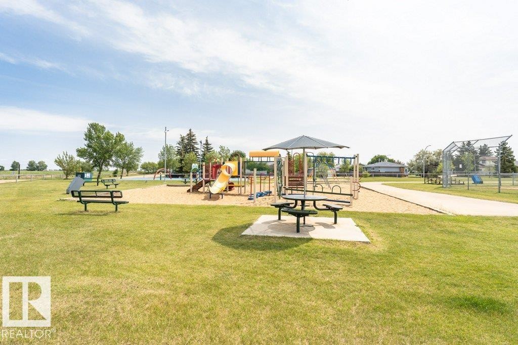 Neighborhood park area featuring a playground with slides, swings, and climbing structures, along with picnic tables and benches - 8 Duke Drive, Lamont, AB - Outdoor