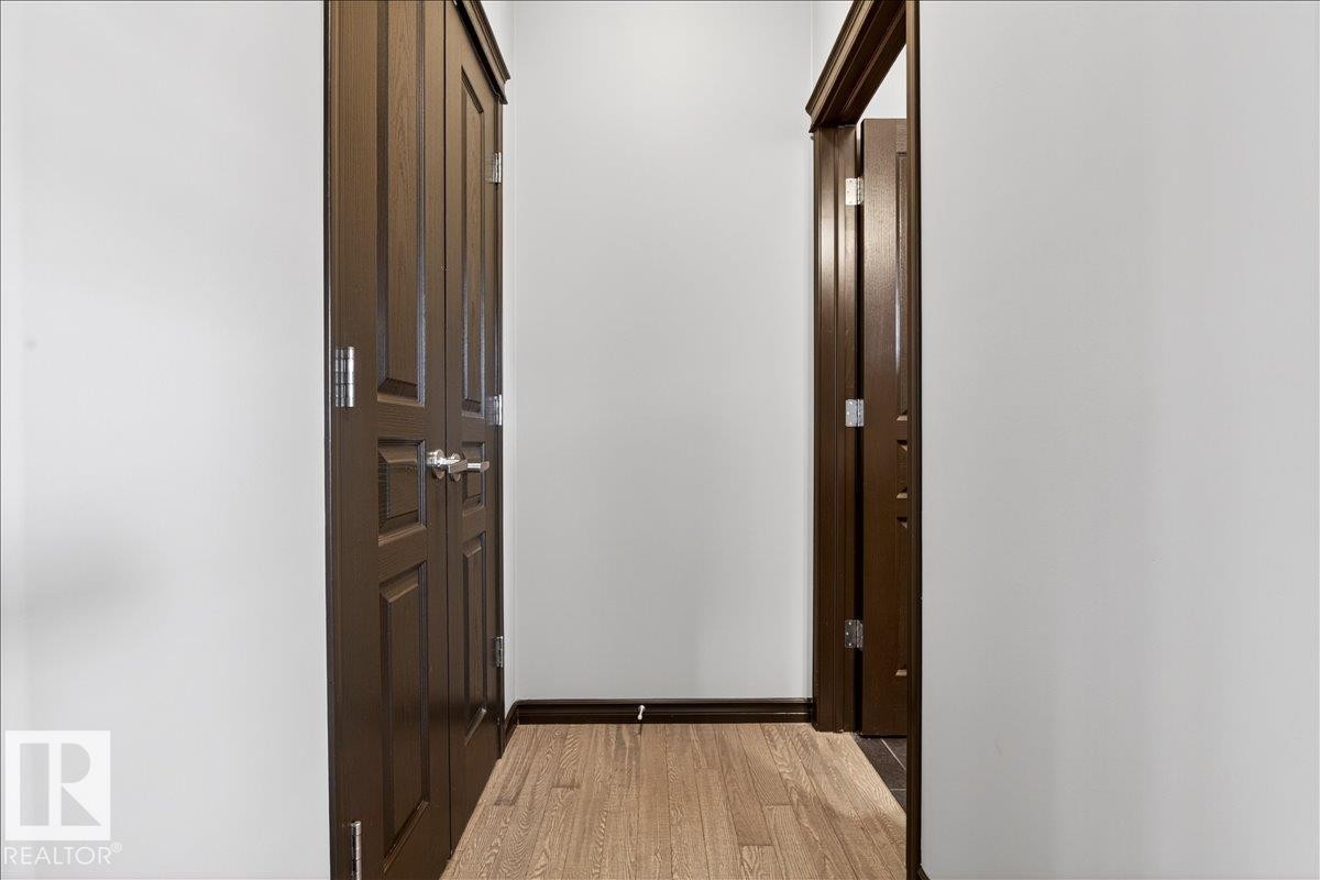 This hallway features durable wood flooring, dark wood trim, and a dark wood bifold door - 1530 Chapman Way, Edmonton, AB - Indoor Photo Showing Other Room
