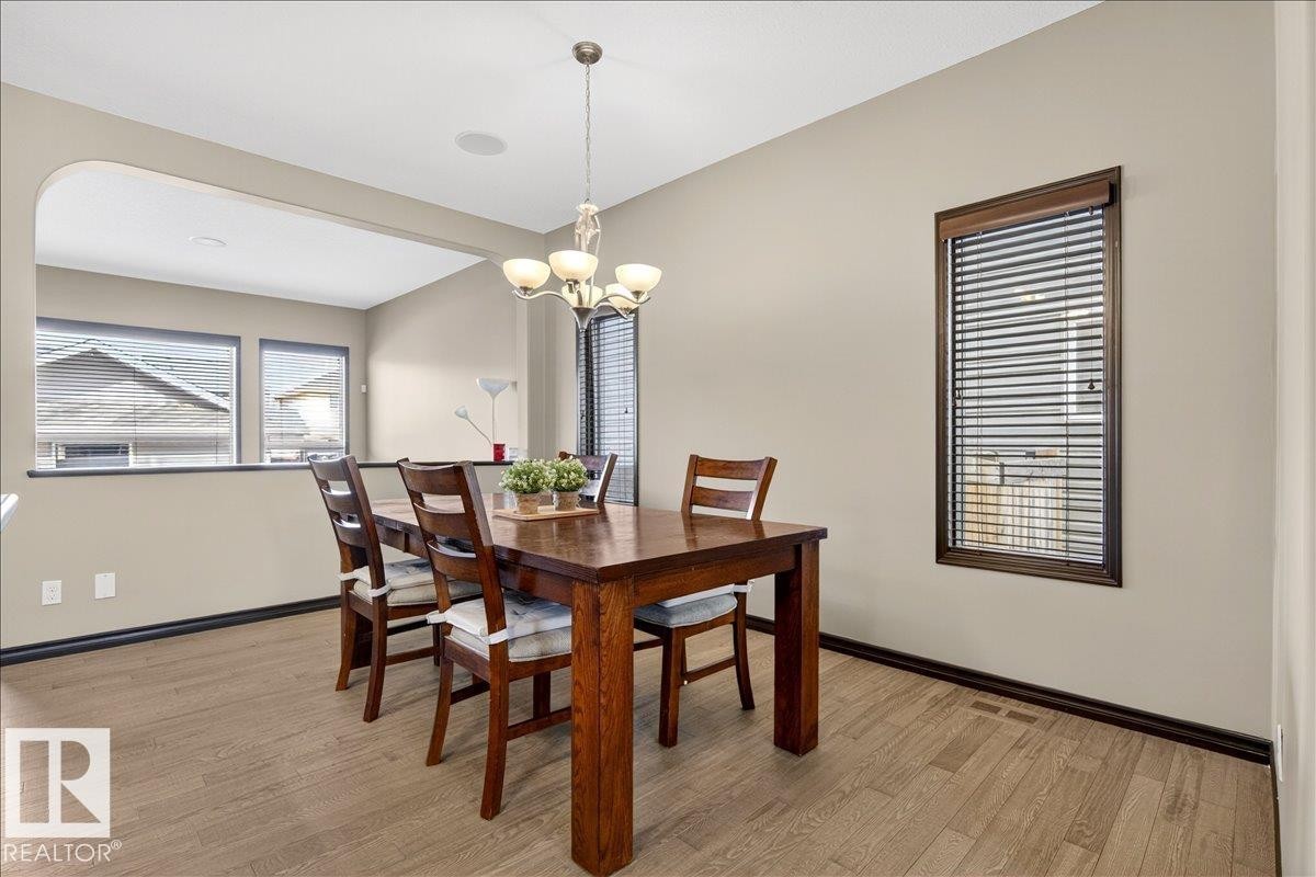 The dining area features light-colored flooring, neutral wall paint, and a chandelier - 1530 Chapman Way, Edmonton, AB - Indoor Photo Showing Dining Room
