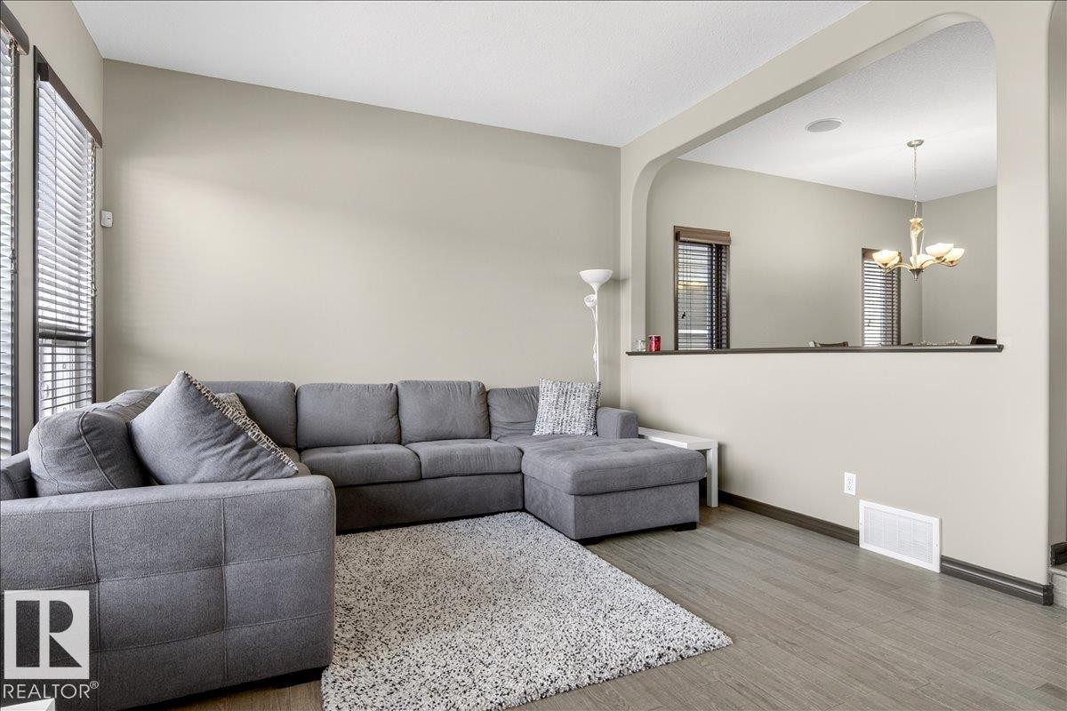 Living area featuring light-colored walls, wood flooring, and large windows with blinds - 1530 Chapman Way, Edmonton, AB - Indoor Photo Showing Living Room