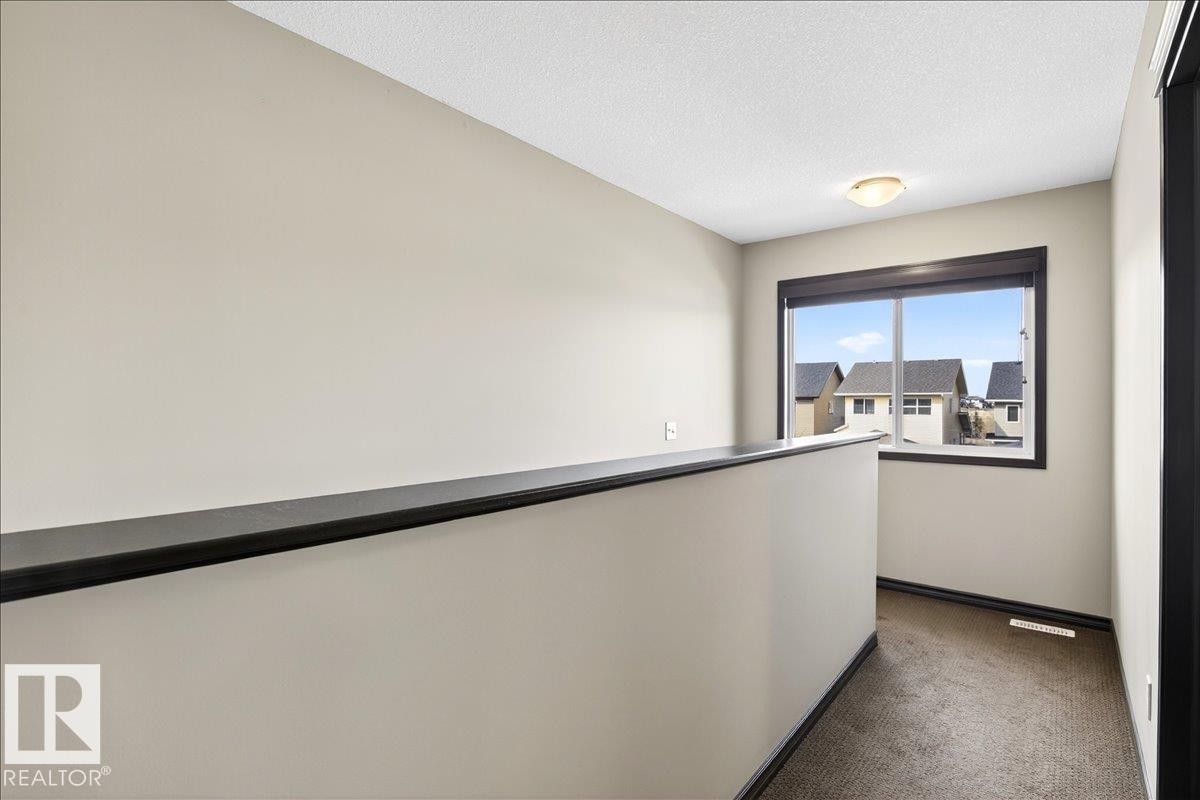 The property features a neutral color palette, carpeted flooring, and a window with views of surrounding properties - 1530 Chapman Way, Edmonton, AB - Indoor Photo Showing Other Room