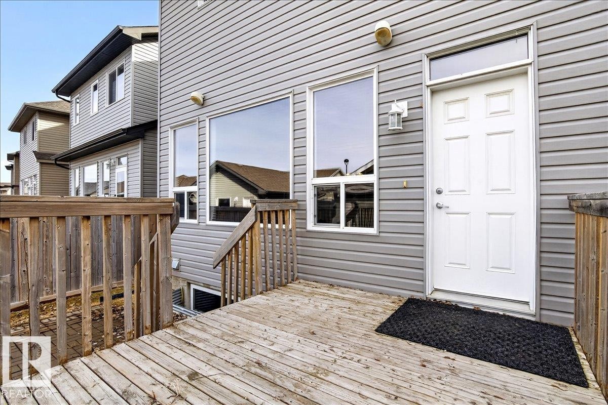 This property features a wooden deck with a matching wooden railing, leading to an exterior door with a transom window - 1530 Chapman Way, Edmonton, AB - Outdoor With Deck Patio Veranda With Exterior