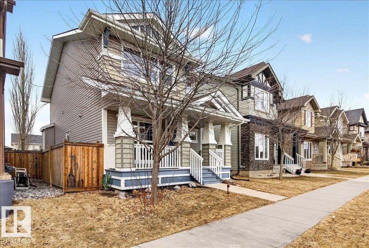This property features a welcoming front porch with white railings and columns, and a light blue base - 1530 Chapman Way, Edmonton, AB - Outdoor With Facade