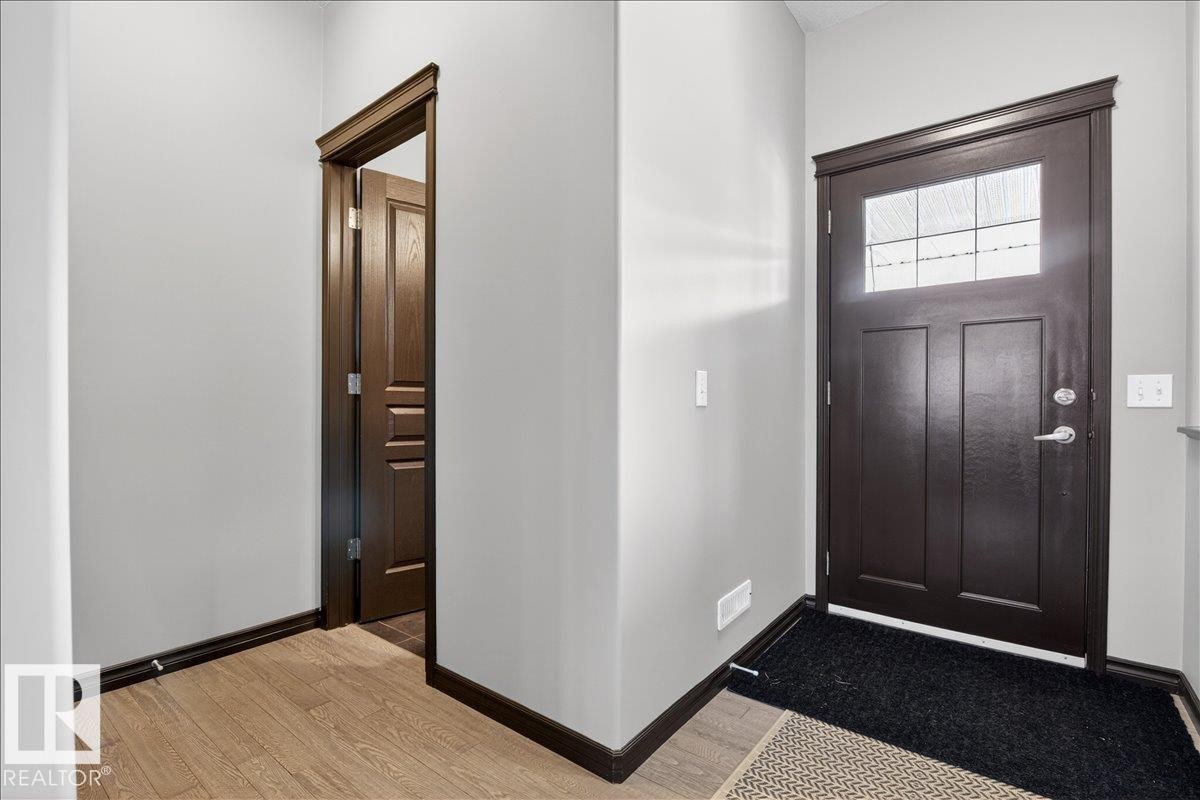 Entryway featuring a dark wood front door with a window, light wood flooring, and neutral-toned walls - 1530 Chapman Way, Edmonton, AB - Indoor Photo Showing Other Room