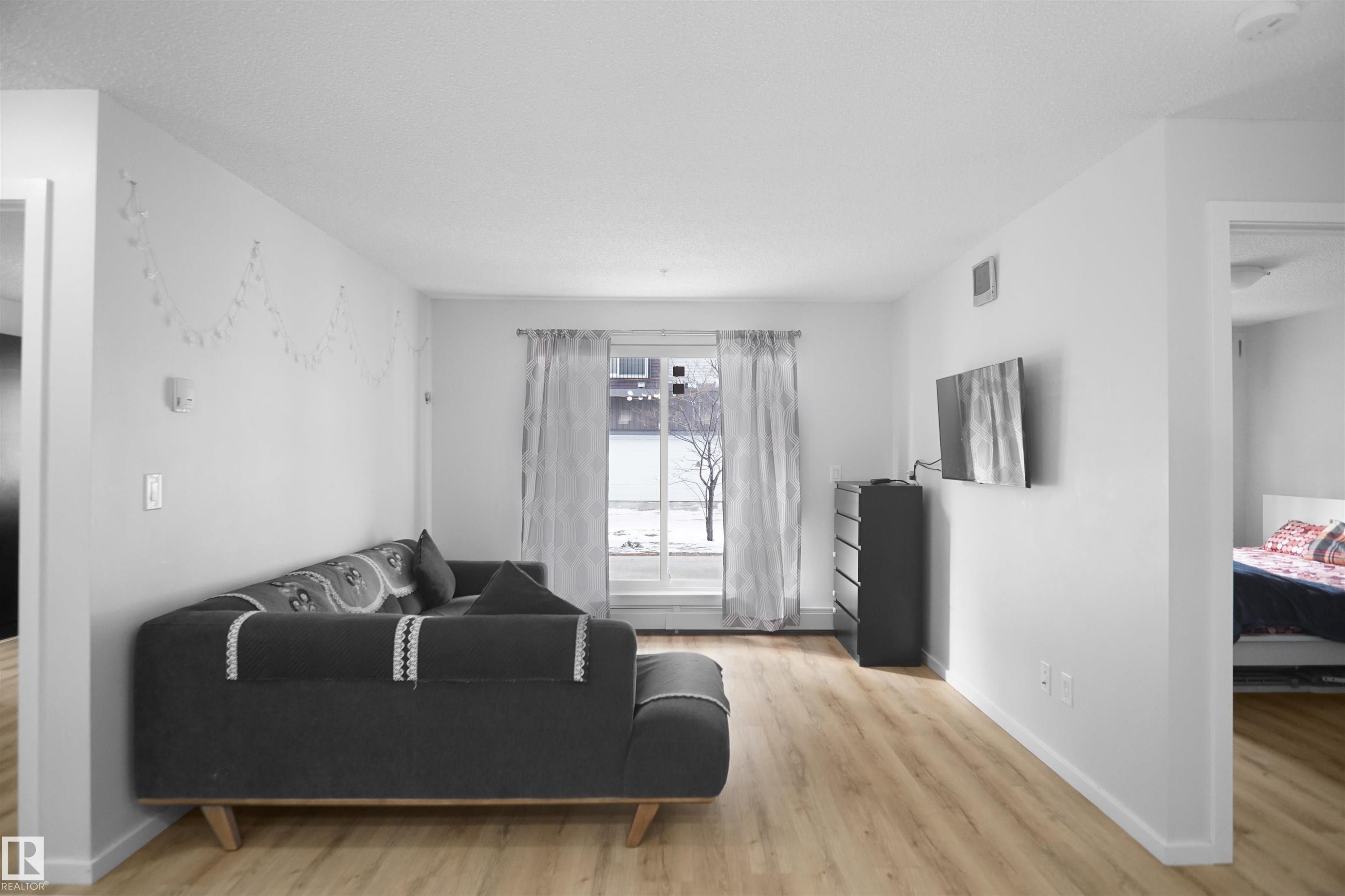 The property features light-colored flooring, white walls, and a window with sheer curtains - 103 3353 16A Avenue, Edmonton, AB - Indoor