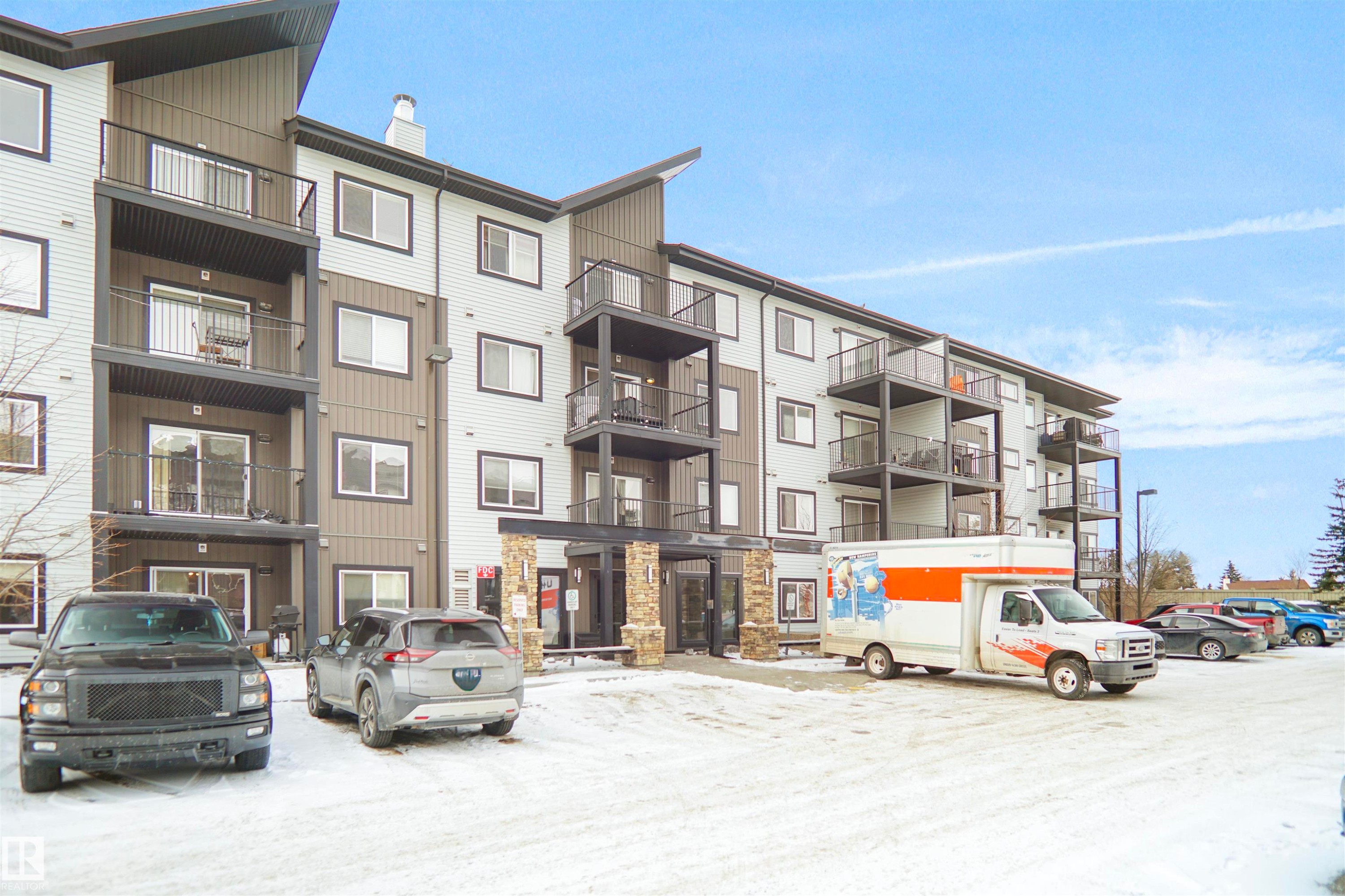This property features a multi-story building with a modern exterior design, incorporating light and dark siding panels - 103 3353 16A Avenue, Edmonton, AB - Outdoor