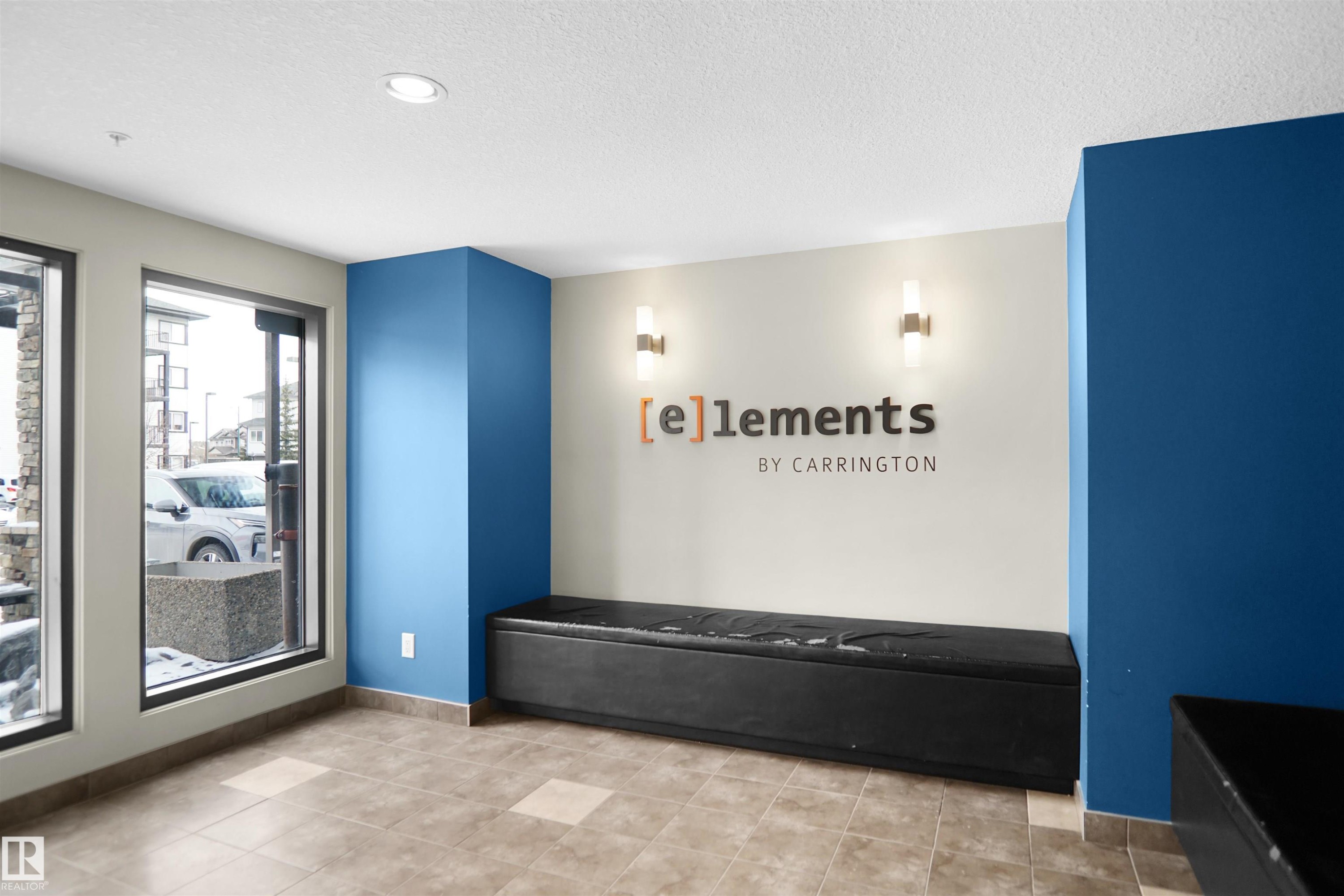 Welcoming lobby area featuring large windows, tiled flooring, and a built-in bench - 103 3353 16A Avenue, Edmonton, AB - Indoor Photo Showing Other Room
