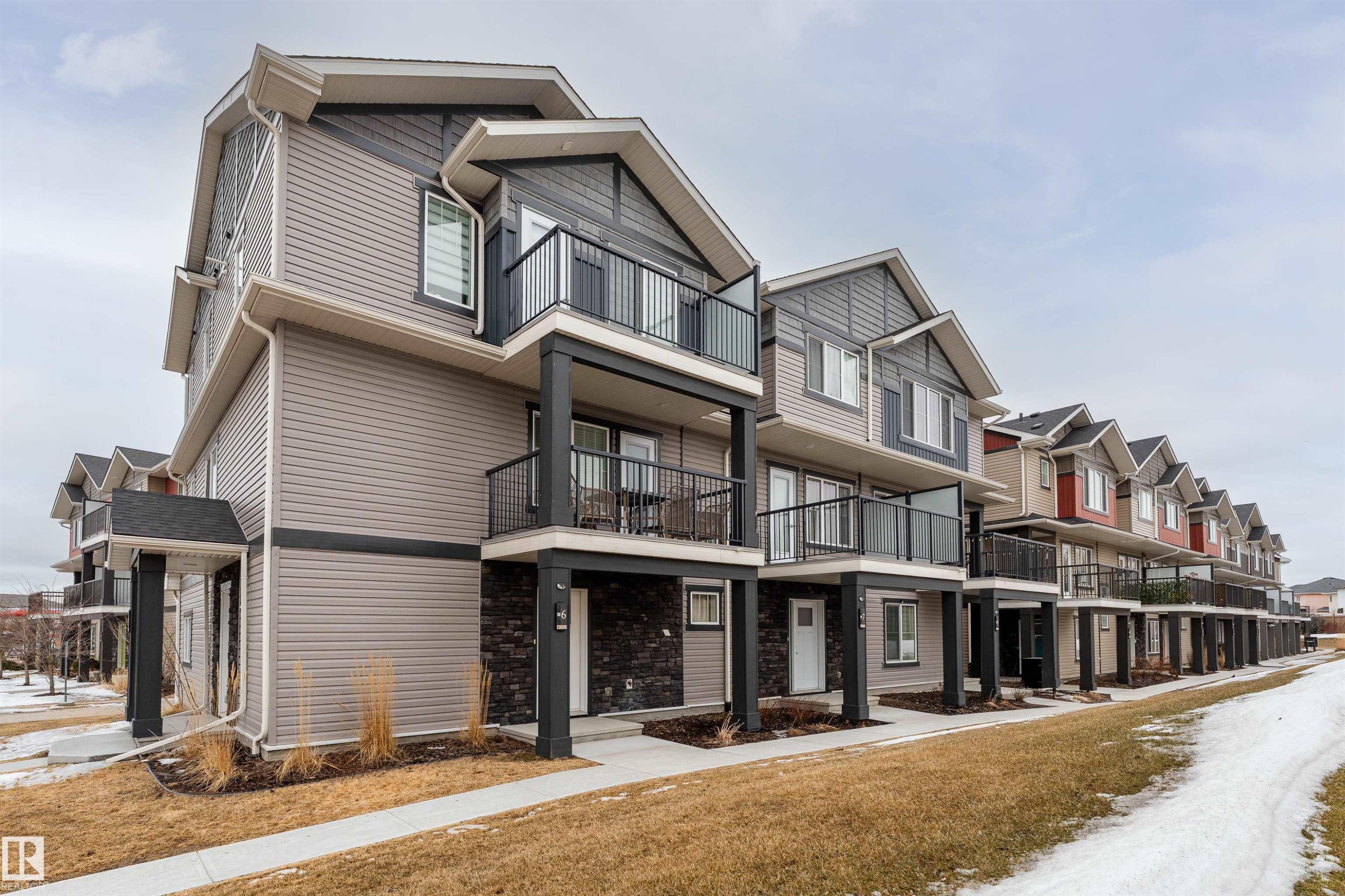 Contemporary townhome-style residences featuring balconies with dark railings, a combination of siding and stone facades, and gabled roofs - 6 12815 Cumberland Rd, Edmonton, AB - Outdoor With Balcony
