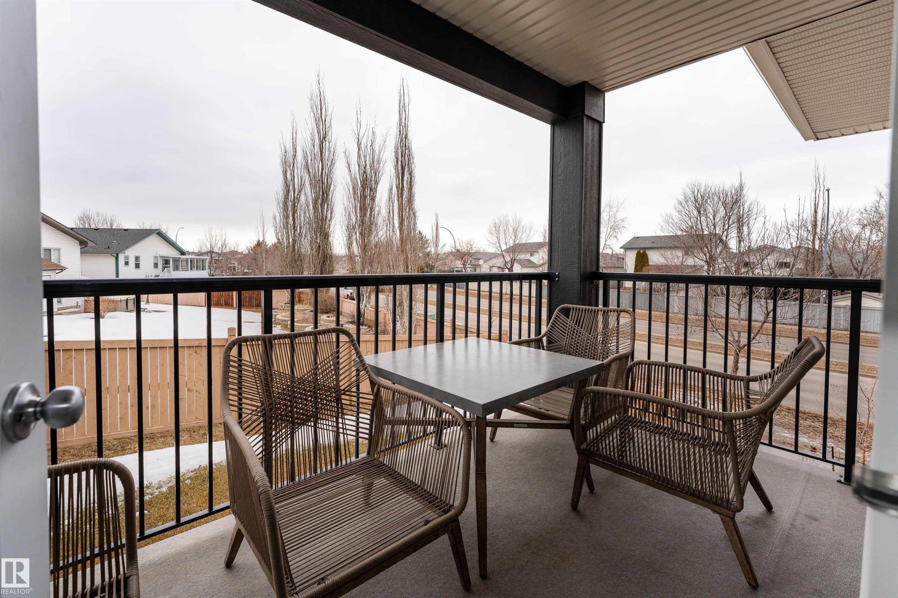 The property features a balcony with a concrete floor and black metal railings, offering a street view - 6 12815 Cumberland Rd, Edmonton, AB - Outdoor With Exterior