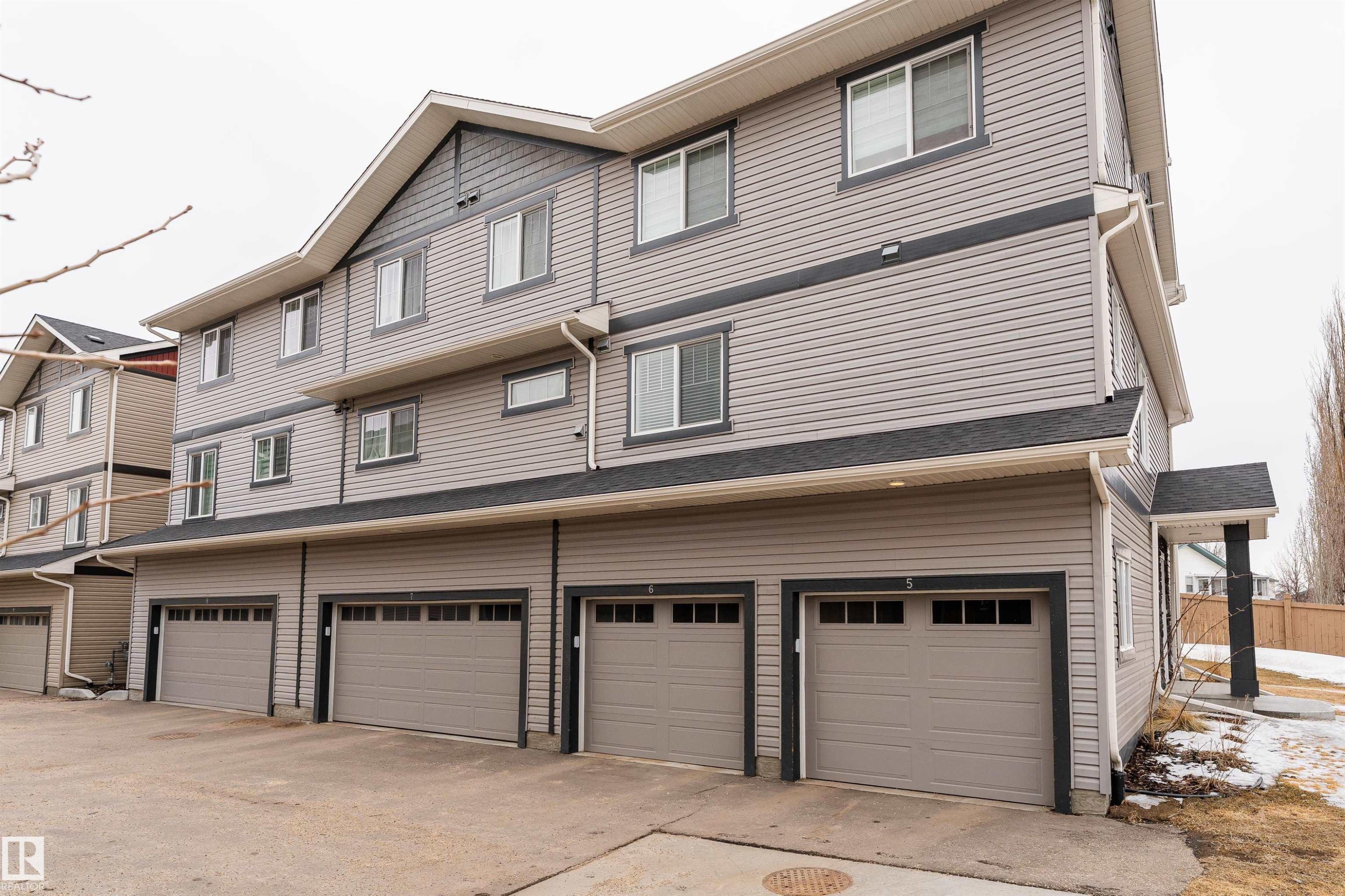 This property features a multi-level design with light gray siding and dark gray trim, offering a contemporary aesthetic - 6 12815 Cumberland Rd, Edmonton, AB - Outdoor With Exterior