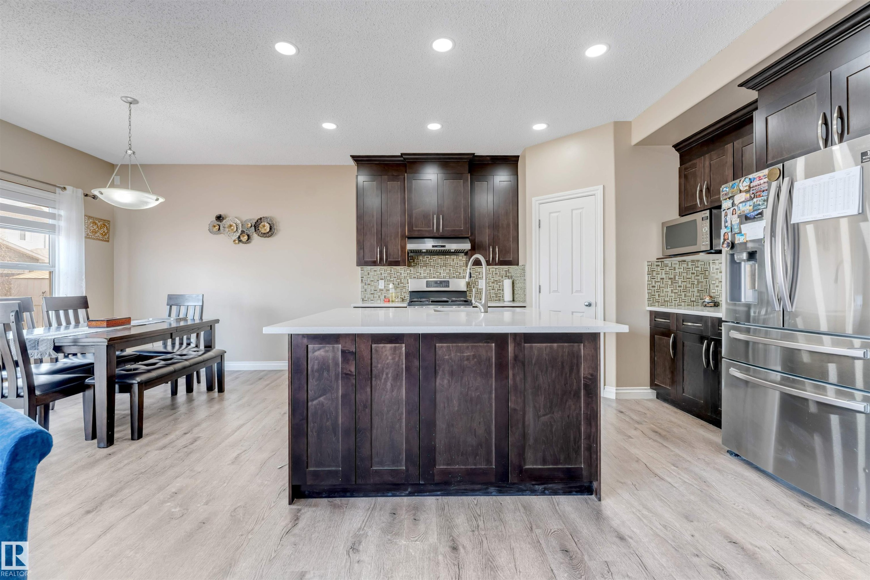 The kitchen features dark wood cabinetry, stainless steel appliances, and a central island with a white countertop - 121 64 Street, Edmonton, AB - Indoor Photo Showing Kitchen With Upgraded Kitchen