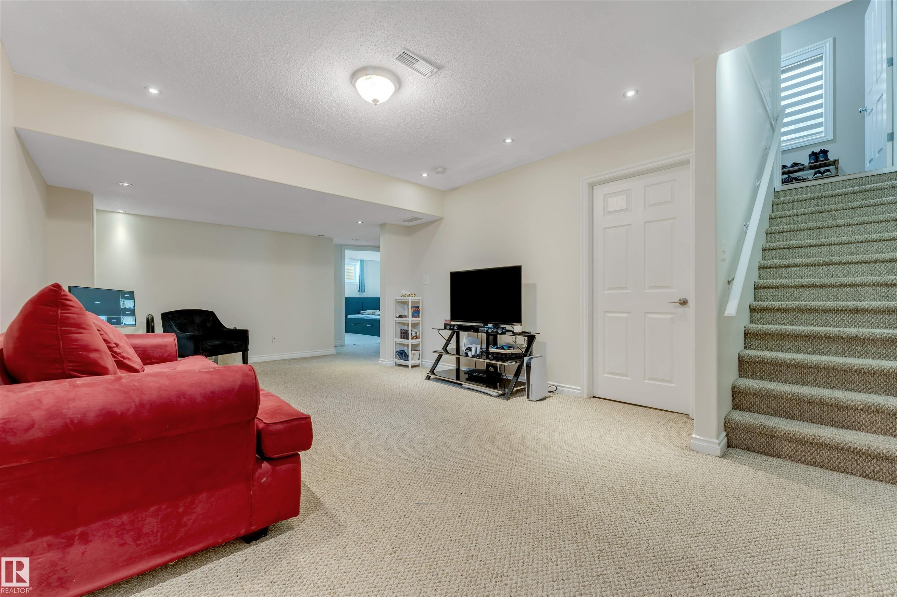 Spacious finished area featuring light-colored carpeting, recessed lighting, and a painted paneled door - 121 64 Street, Edmonton, AB - Indoor