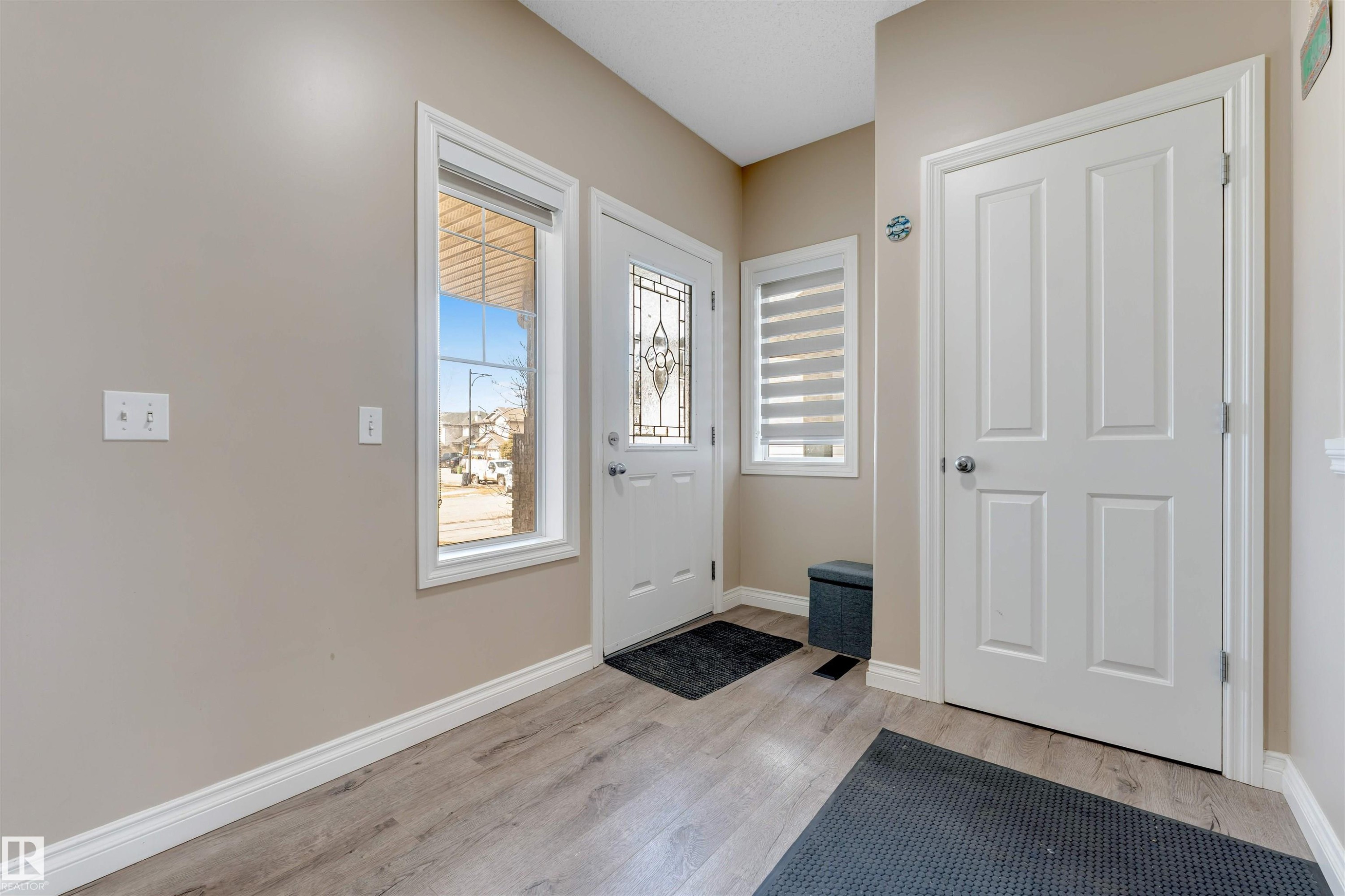 Entryway featuring wood-look flooring, light-colored walls, white trim, and a front door with decorative glass - 121 64 Street, Edmonton, AB - Indoor Photo Showing Other Room