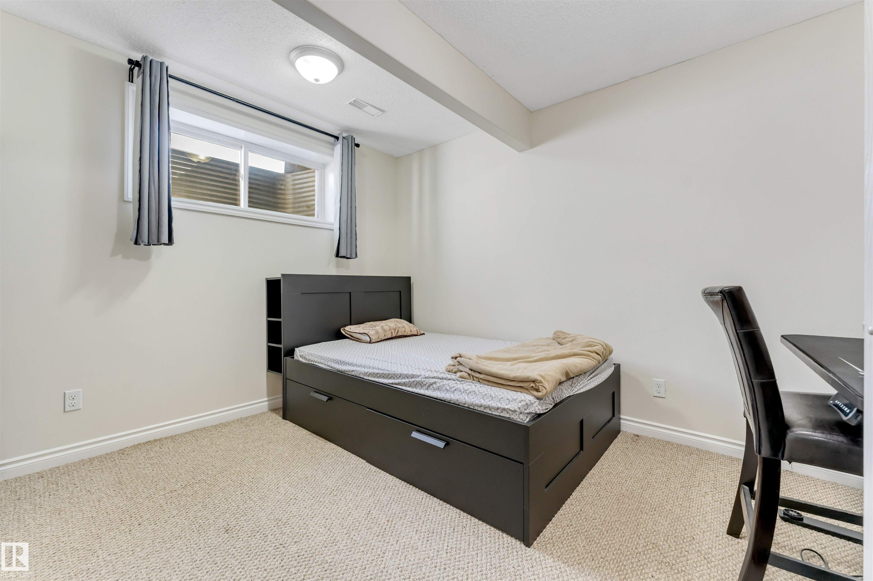 This room features light-colored carpeted flooring, a window with horizontal blinds and curtains, and a ceiling-mounted light fixture - 121 64 Street, Edmonton, AB - Indoor Photo Showing Bedroom
