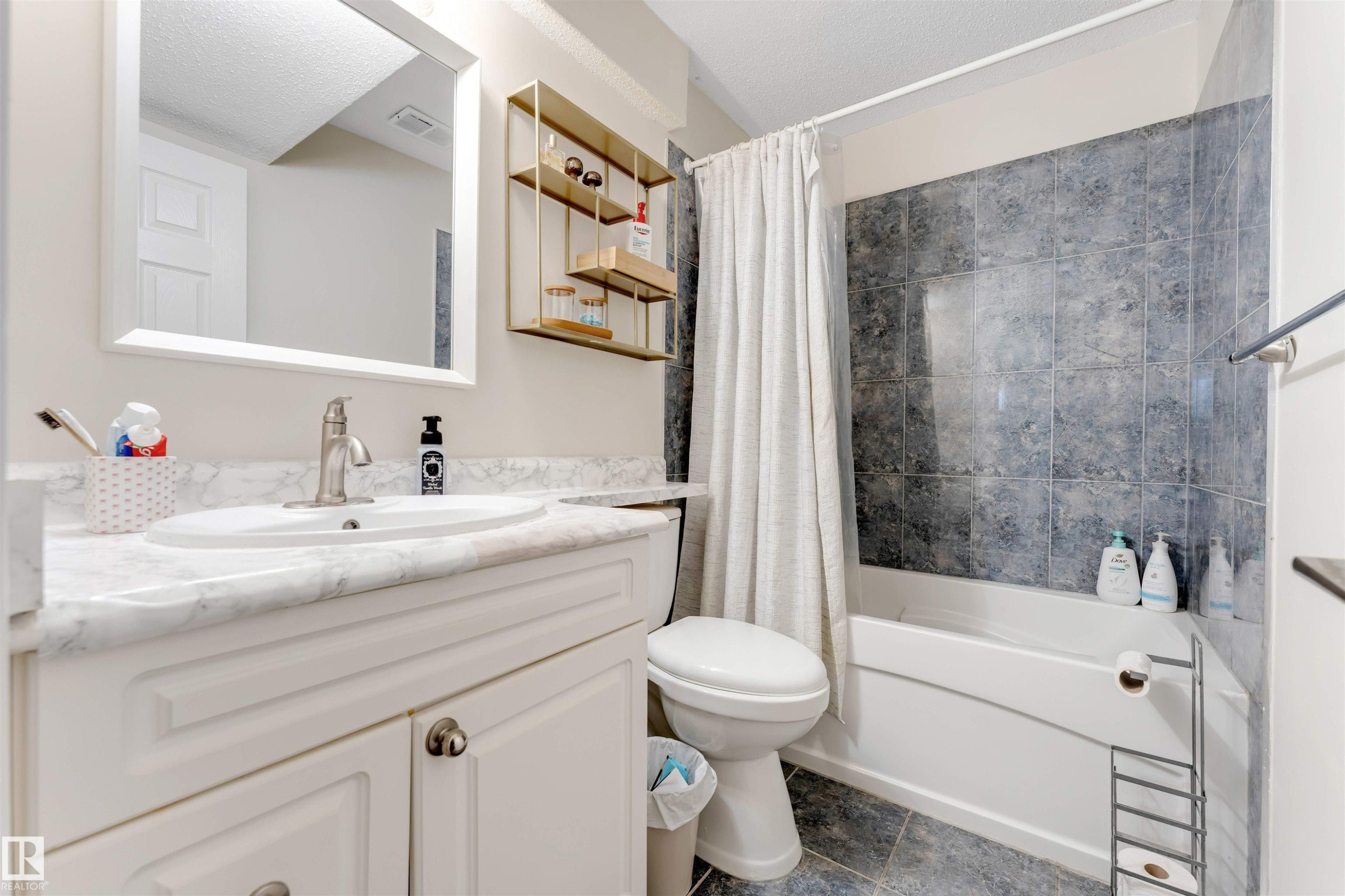 Well-appointed bathroom featuring a vanity with a white countertop and sink, a mirror, and a bathtub with tiled surround - 121 64 Street, Edmonton, AB - Indoor Photo Showing Bathroom