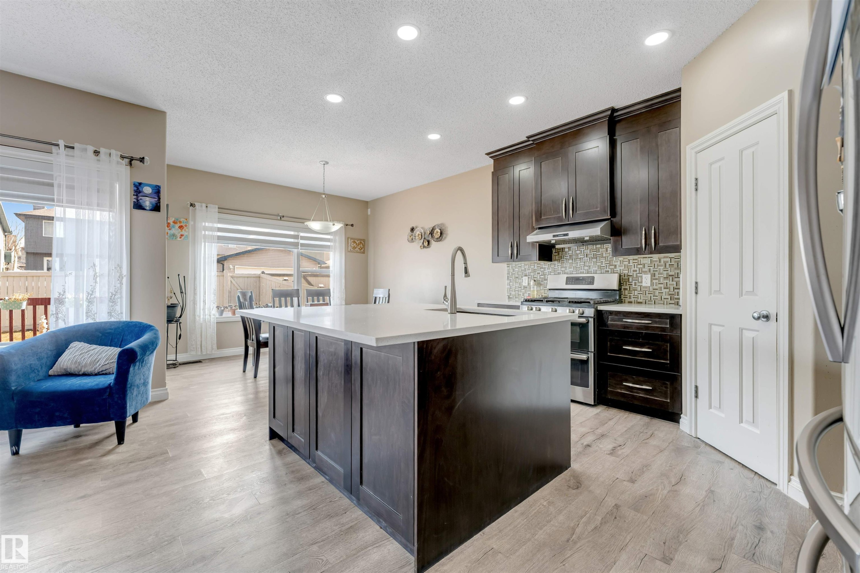 The kitchen features dark wood cabinetry, stainless steel appliances, and a tiled backsplash - 121 64 Street, Edmonton, AB - Indoor Photo Showing Kitchen With Upgraded Kitchen