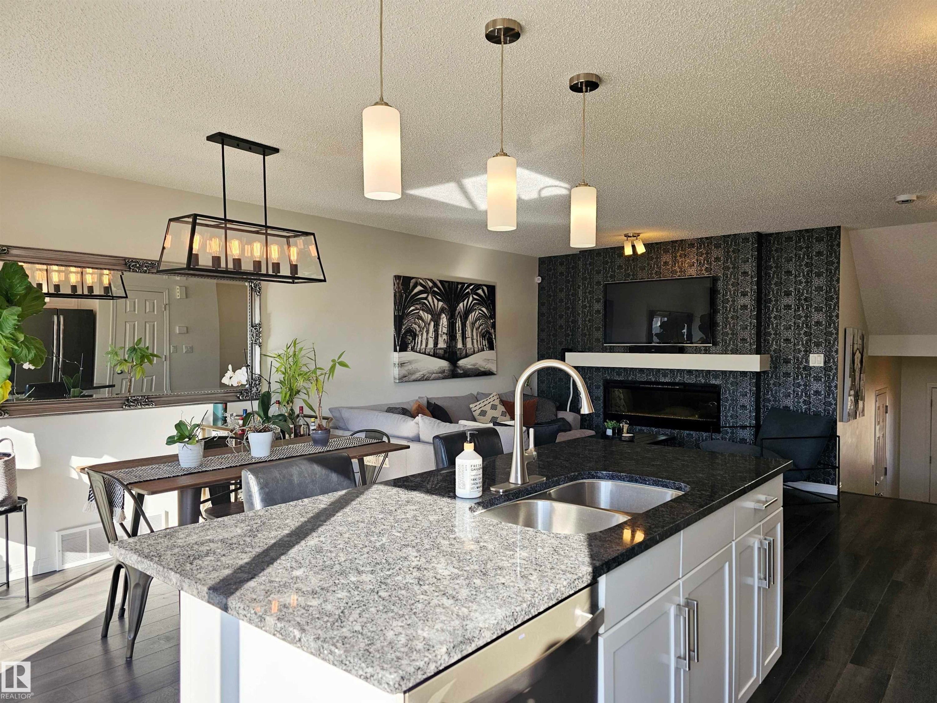 The property features an open concept living area with a kitchen island with a double basin sink and a stone countertop - 6888 Evans Wynd, Edmonton, AB - Indoor Photo Showing Kitchen With Double Sink