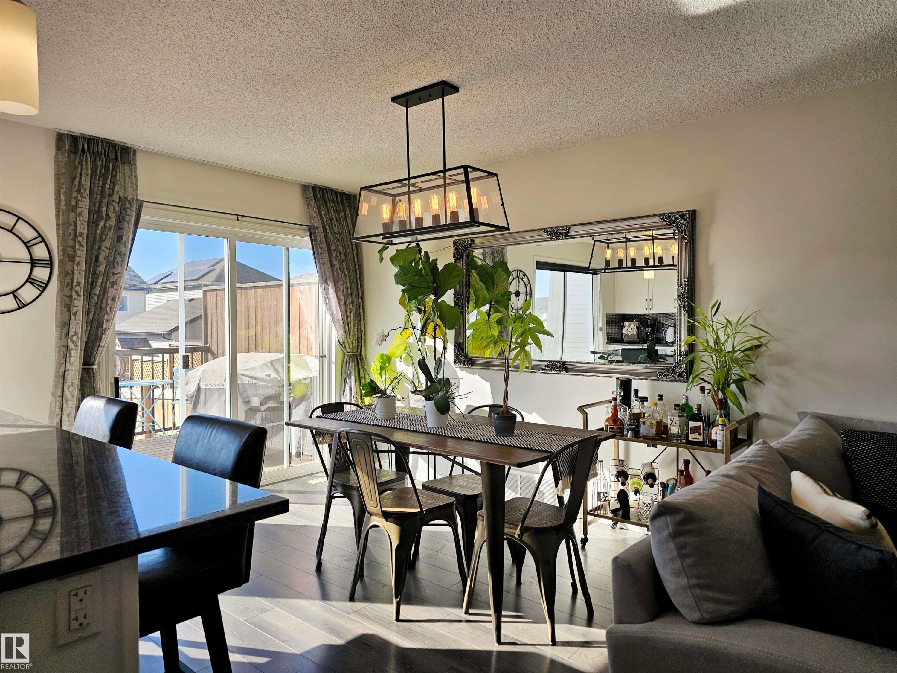 This inviting living space features dark hardwood flooring and a contemporary chandelier - 6888 Evans Wynd, Edmonton, AB - Indoor