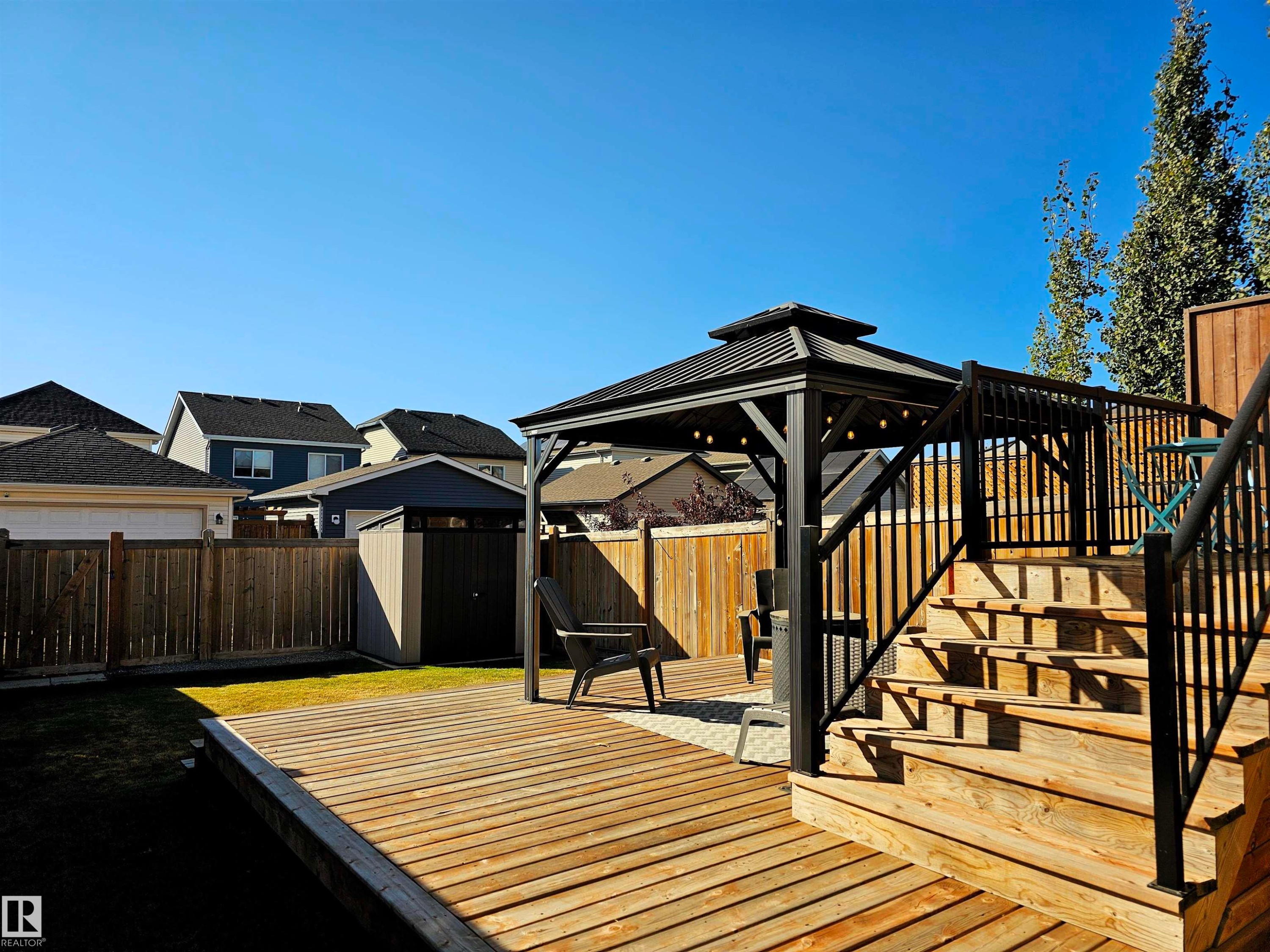 Spacious backyard featuring a large wooden deck with a gazebo, steps, and railing - 6888 Evans Wynd, Edmonton, AB - Outdoor With Exterior