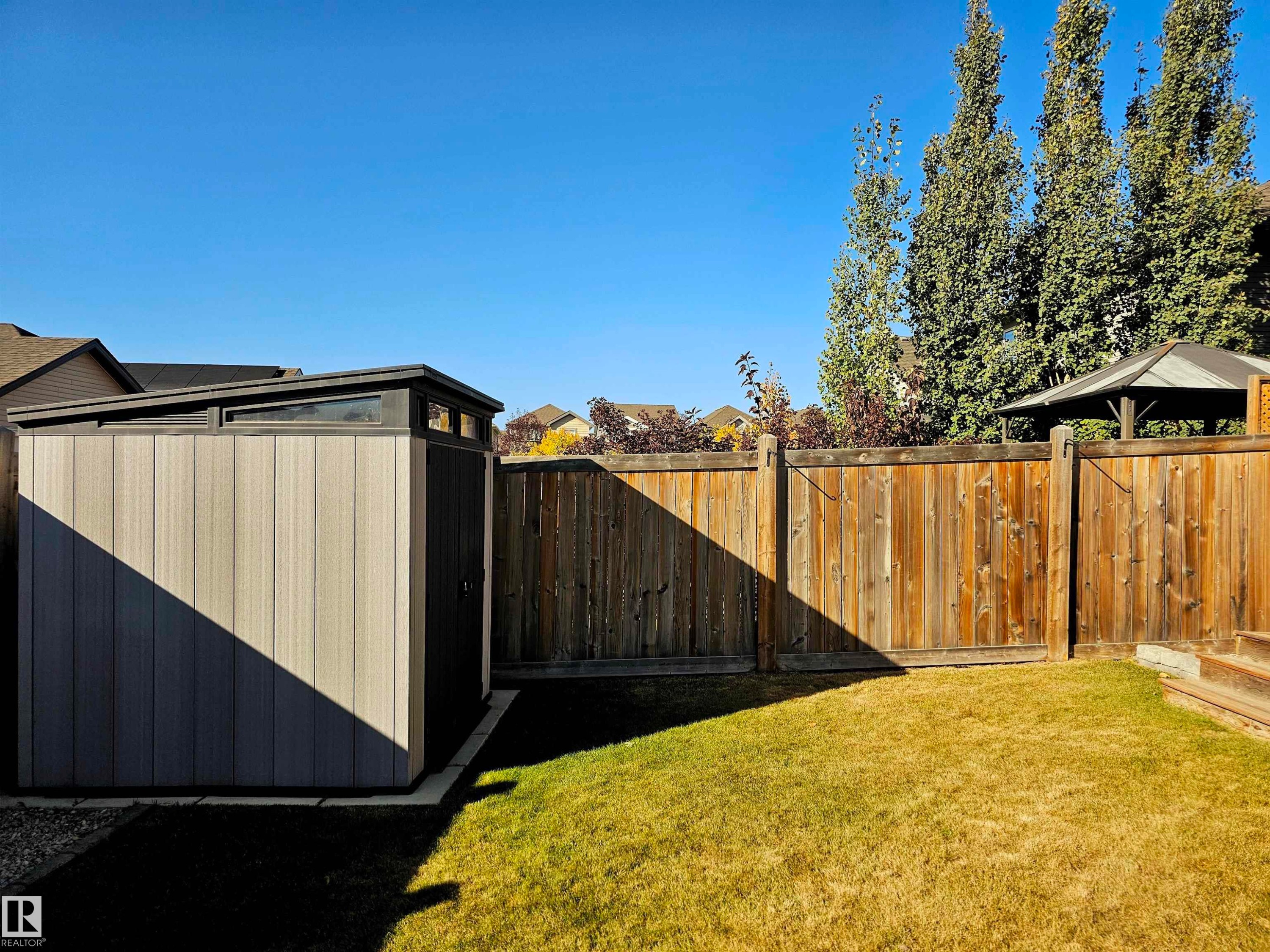 The property features a well-maintained yard with a lawn, a wooden fence, and a storage shed with a sloped roof - 6888 Evans Wynd, Edmonton, AB - Outdoor