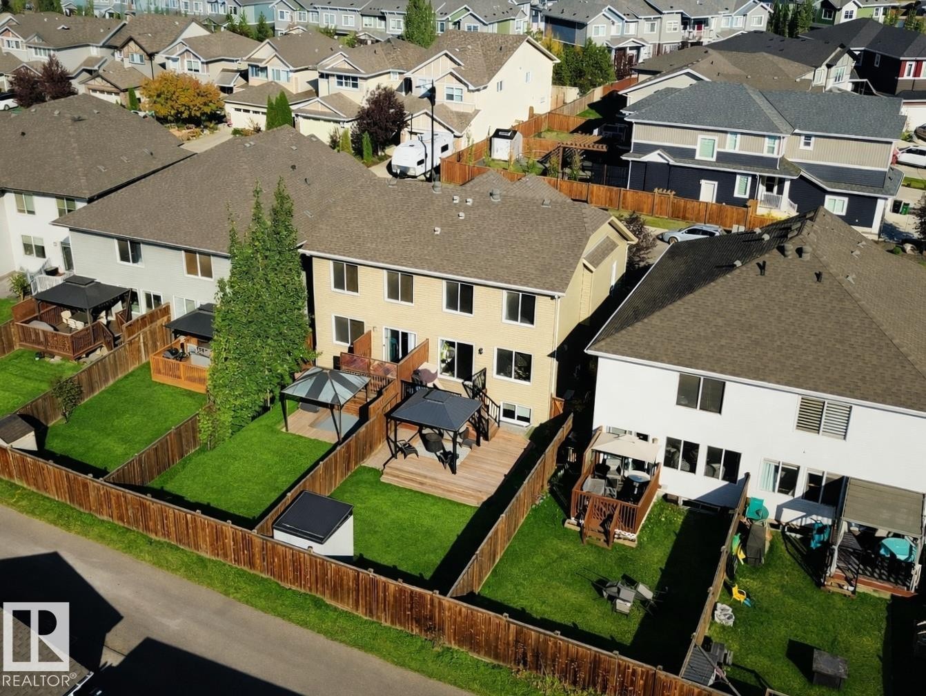 The property features a spacious backyard with a well-maintained lawn, a wooden deck, and a gazebo - 6888 Evans Wynd, Edmonton, AB - Outdoor With Deck Patio Veranda