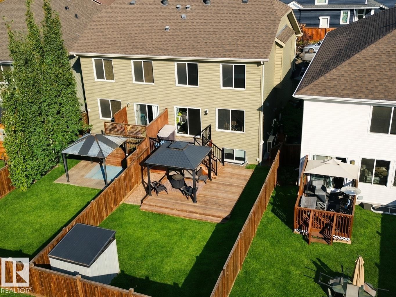 The property features a spacious backyard with a well-maintained lawn, a large wooden deck, and a shed - 6888 Evans Wynd, Edmonton, AB - Outdoor With Deck Patio Veranda With Exterior