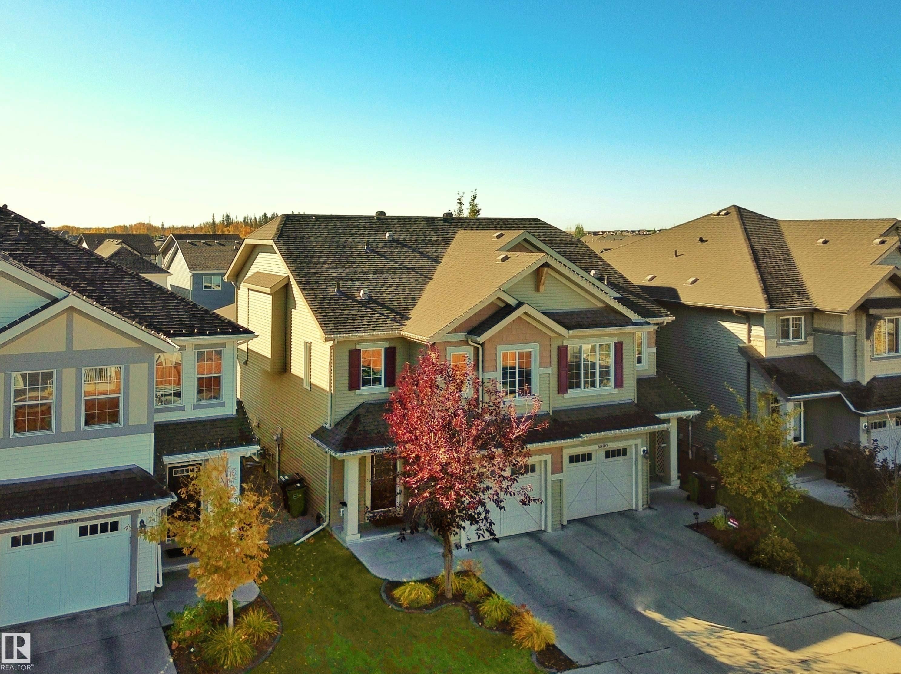 The property features a two-story design with a light-colored exterior and contrasting dark roof - 6888 Evans Wynd, Edmonton, AB - Outdoor With Facade