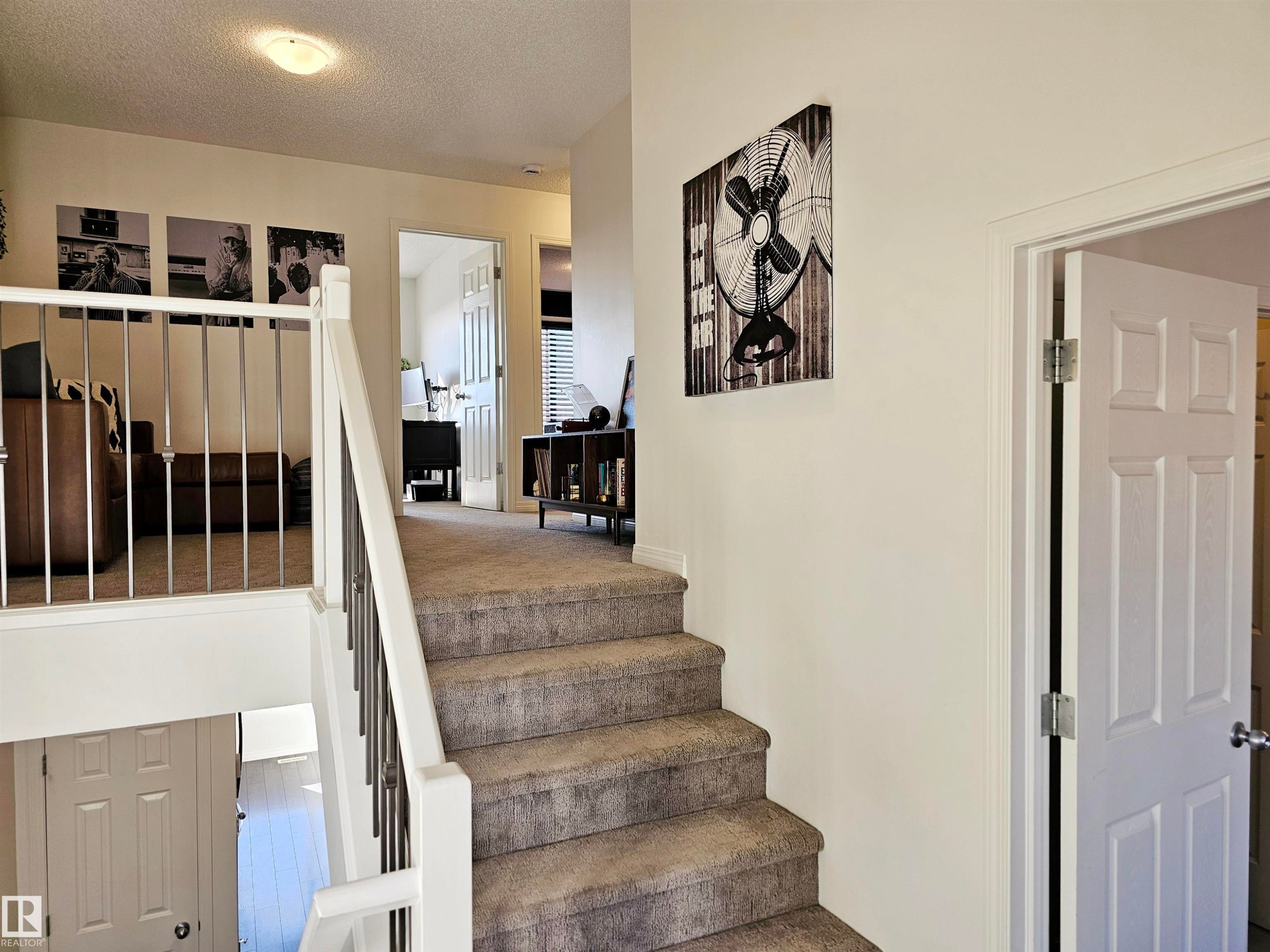 Well-maintained staircase with light-colored carpet, white risers, and a white and silver railing - 6888 Evans Wynd, Edmonton, AB - Indoor Photo Showing Other Room