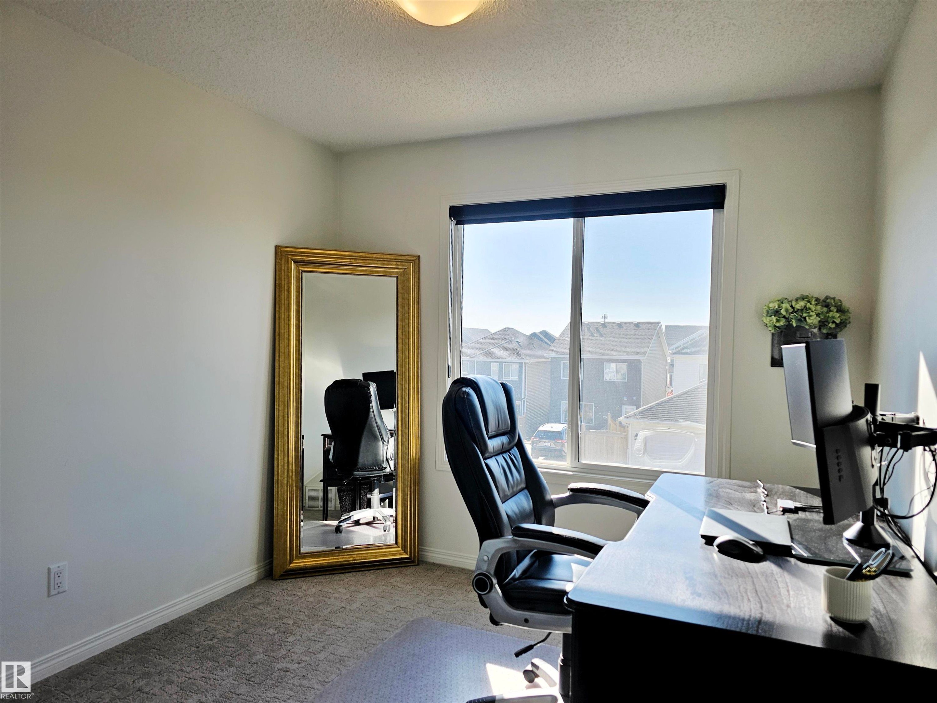 This room features a window with a view of the surrounding neighborhood, light-colored walls, and textured carpeting - 6888 Evans Wynd, Edmonton, AB - Indoor Photo Showing Office