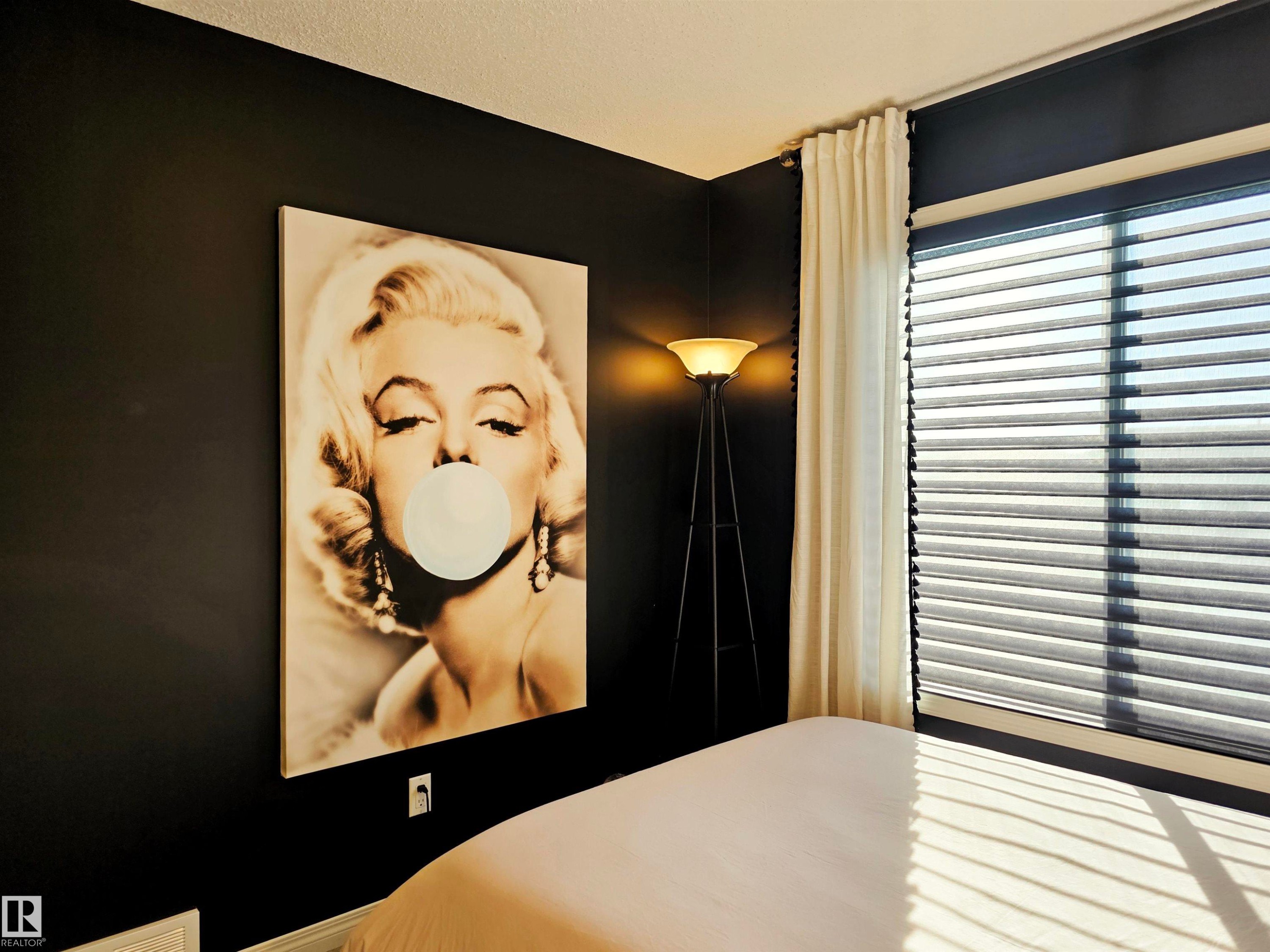 The room features dark walls, a window with horizontal blinds, and a floor lamp with an inverted bowl-shaped shade - 6888 Evans Wynd, Edmonton, AB - Indoor