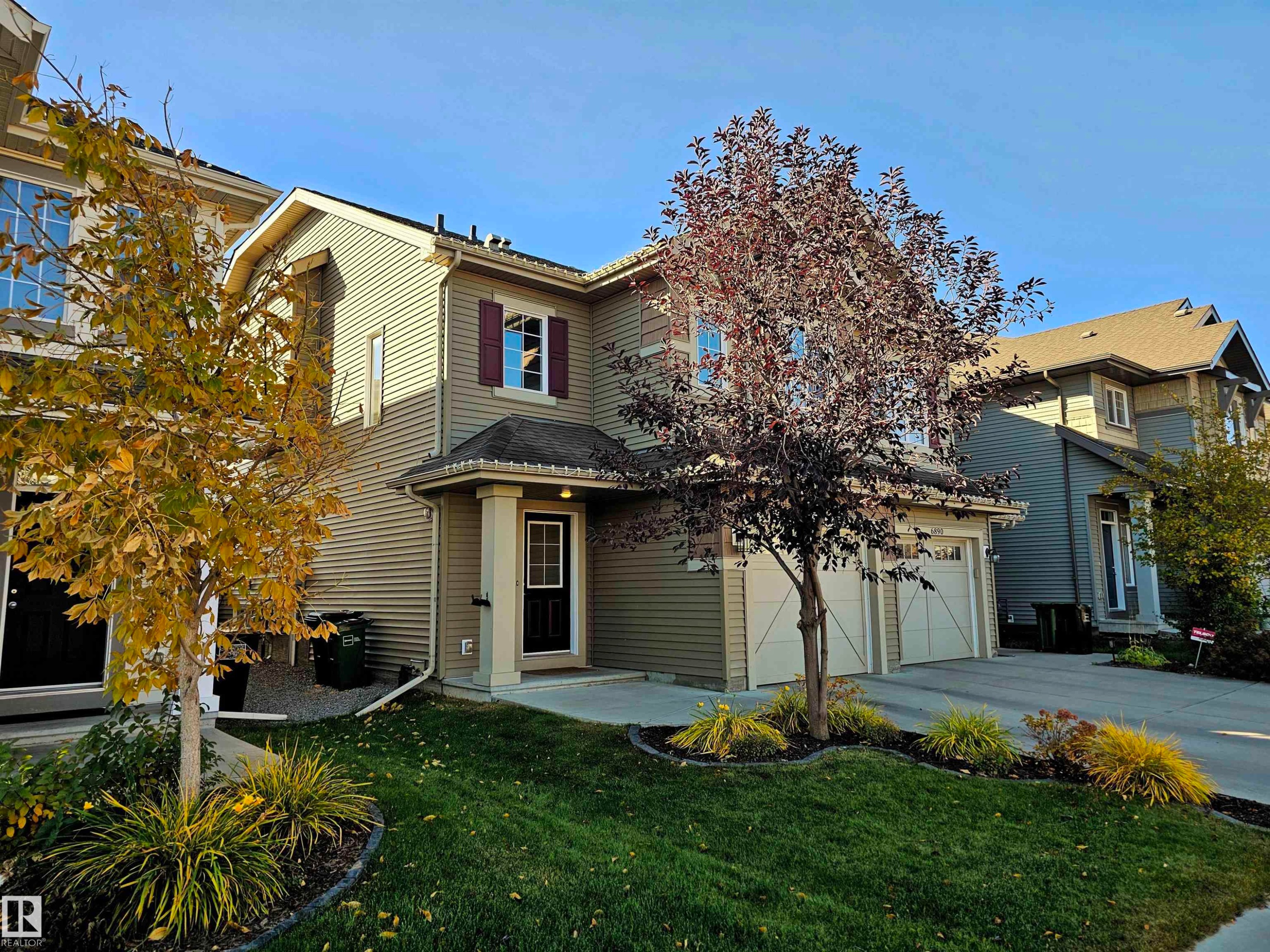 The property features a two-story exterior with horizontal siding, a covered entry, and a two-car garage - 6888 Evans Wynd, Edmonton, AB - Outdoor