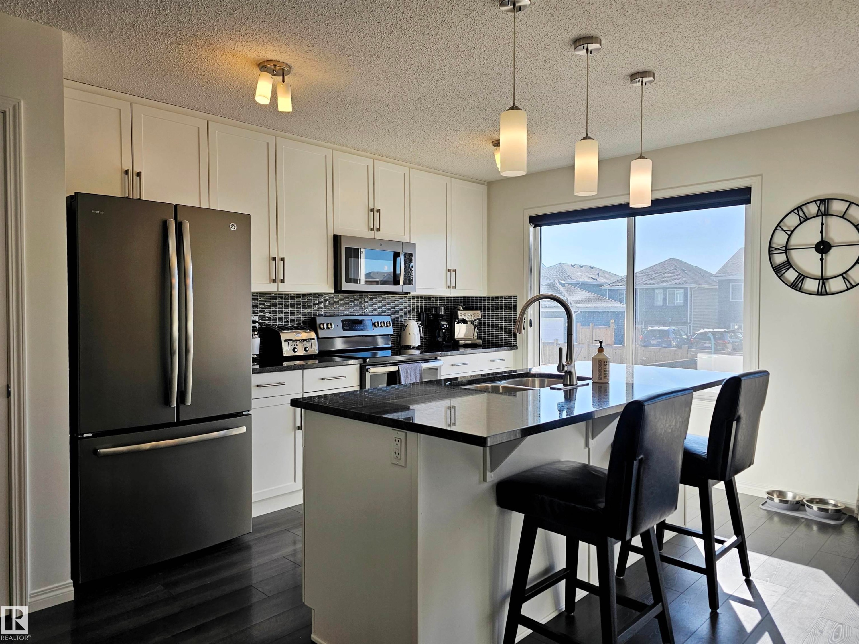 Well-appointed kitchen featuring a large window, dark wood floors, white cabinetry, and stainless steel appliances - 6888 Evans Wynd, Edmonton, AB - Indoor Photo Showing Kitchen With Stainless Steel Kitchen With Upgraded Kitchen