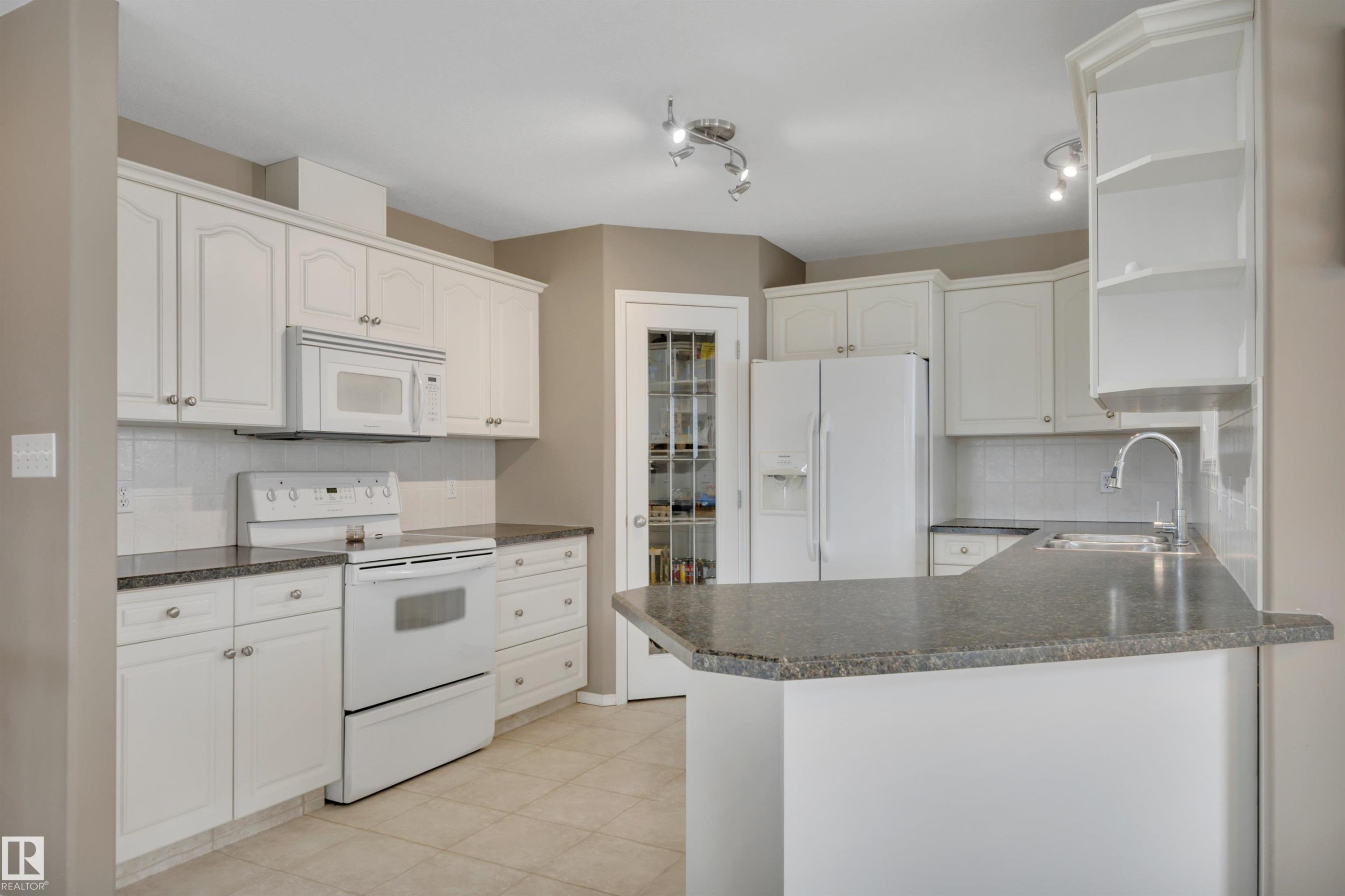 The kitchen features white cabinetry, granite countertops, and white appliances including a refrigerator, oven, and microwave - 5 Parkview Crescent, Calmar, AB - Indoor Photo Showing Kitchen