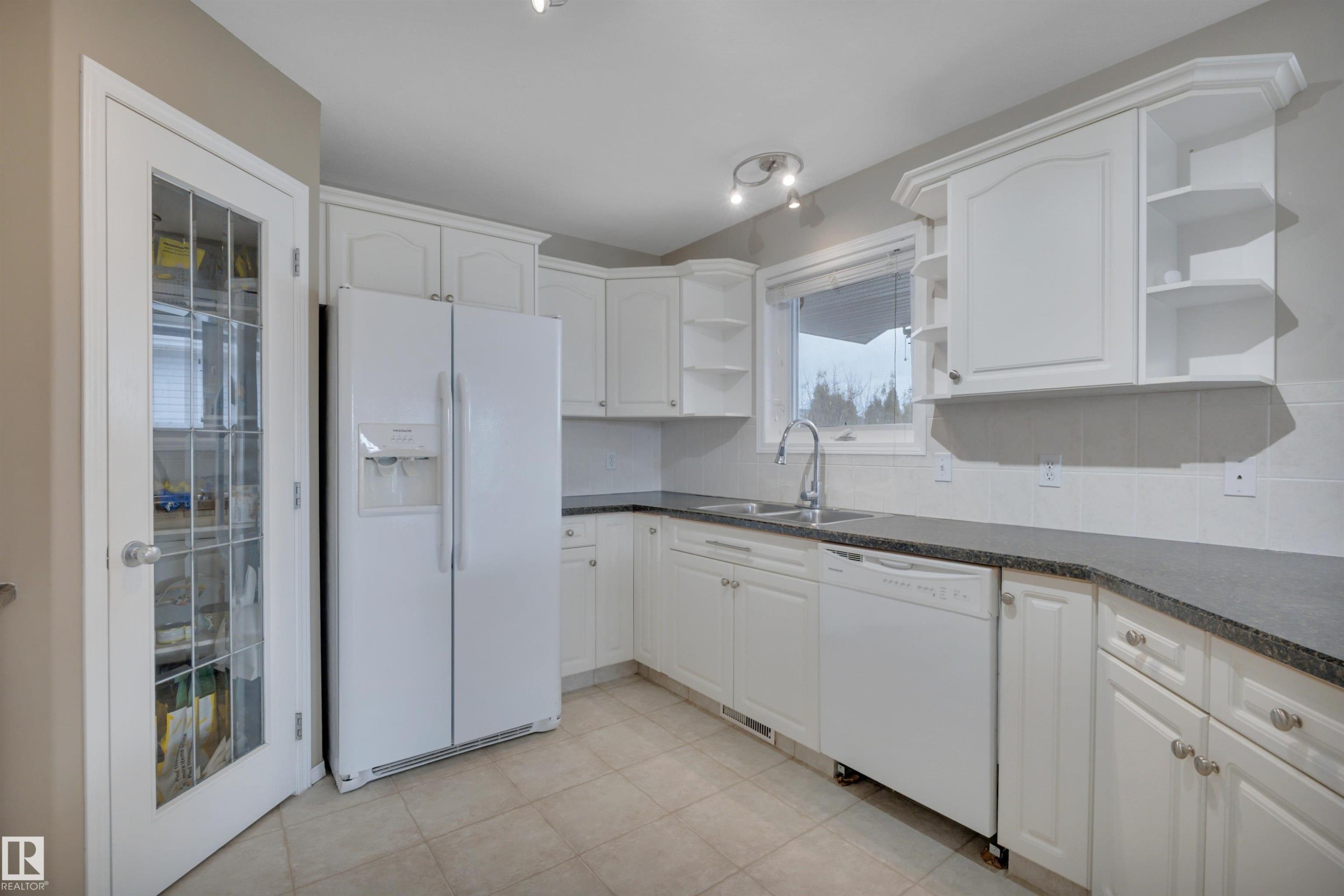Kitchen featuring white cabinetry, dark countertops, a window over the sink, and tile flooring - 5 Parkview Crescent, Calmar, AB - Indoor Photo Showing Kitchen