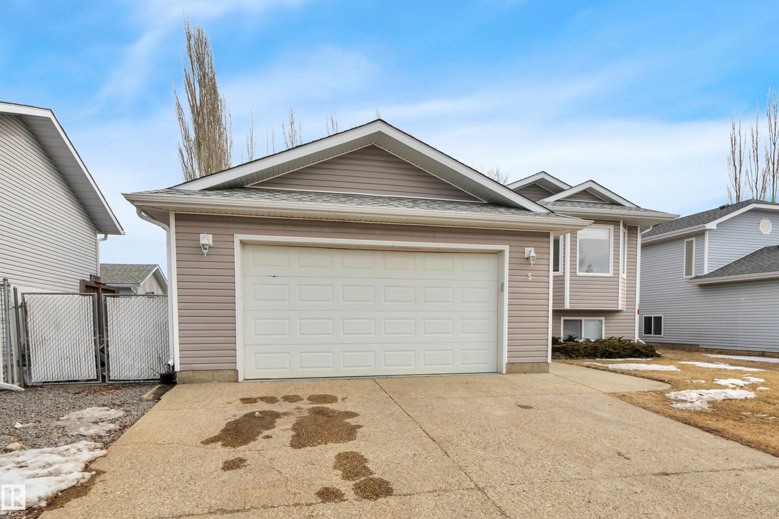 The property features a two-car garage with a panel door, light-colored siding, and a concrete driveway - 5 Parkview Crescent, Calmar, AB - Outdoor